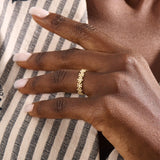 Model wears a 14k gold eternity band ring featuring small daisy flowers. Perfect for stacking or as a charming everyday statement piece