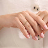 Model wears a 14k gold eternity band ring with geometric rhombus shapes and moissanite accents. A striking and contemporary statement piece.