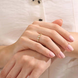 Model wears a 14k gold eternity band ring with geometric rhombus shapes and moissanite accents. A striking and contemporary statement piece.