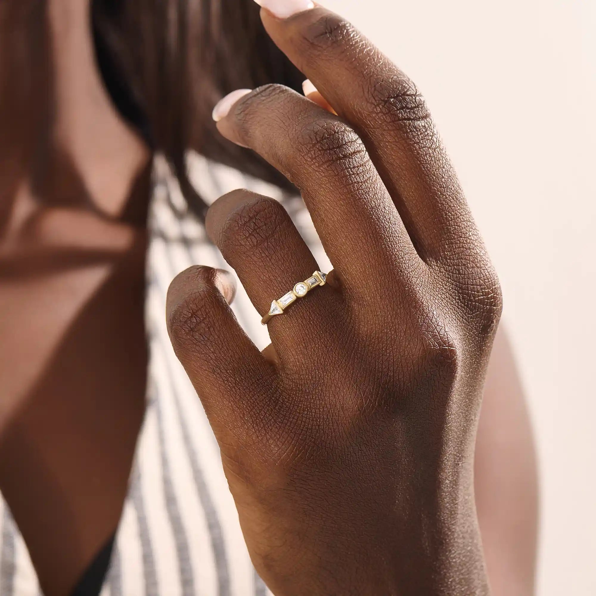 Model wears a 14k gold half eternity statement ring with bezel-set mixed cut stones. A bold and stylish piece for everyday wear.