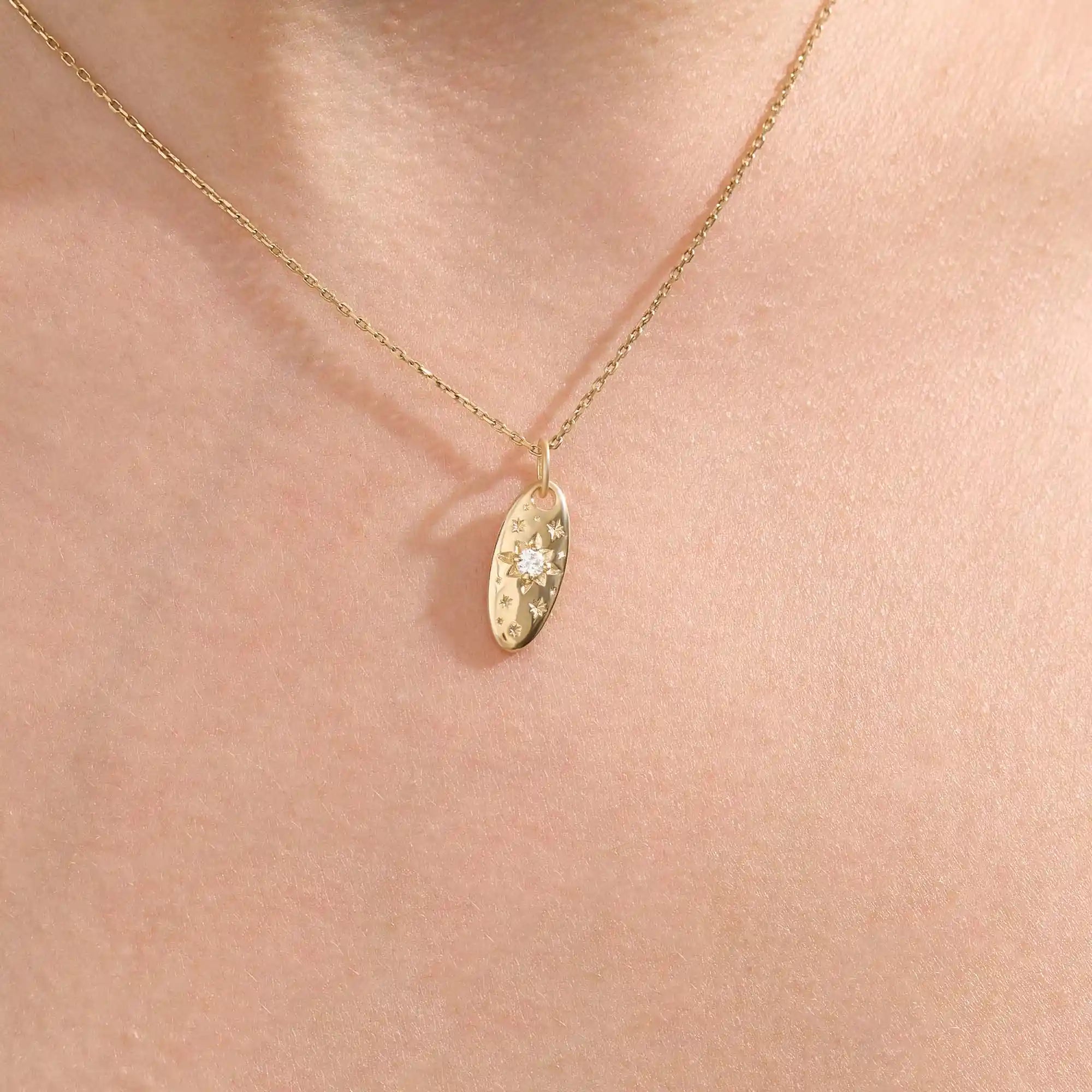 Model wears a 14k gold oval celestial pendant necklace with moissanite Northstar detail. A refined and meaningful accessory for everyday wear.