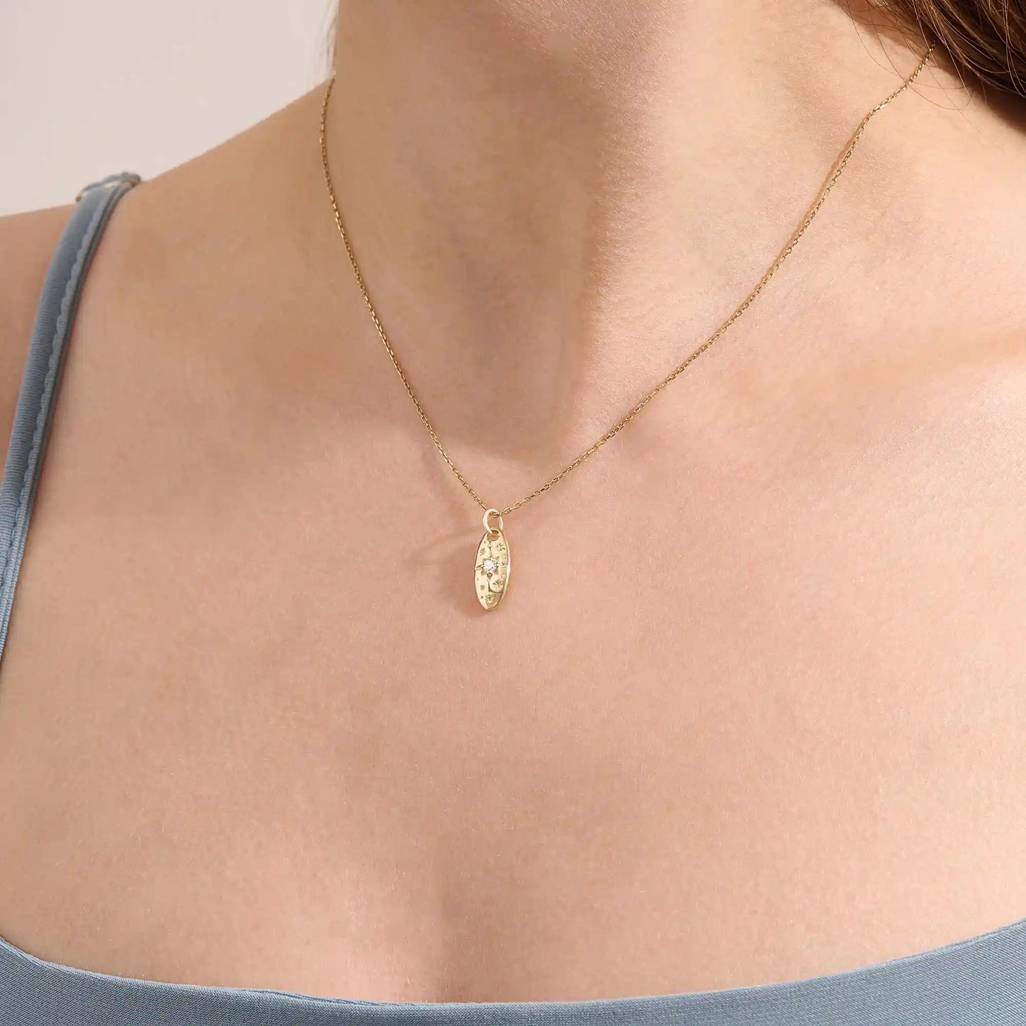 Model wears a 14k gold oval celestial pendant necklace with moissanite Northstar detail. A refined and meaningful accessory for everyday wear.