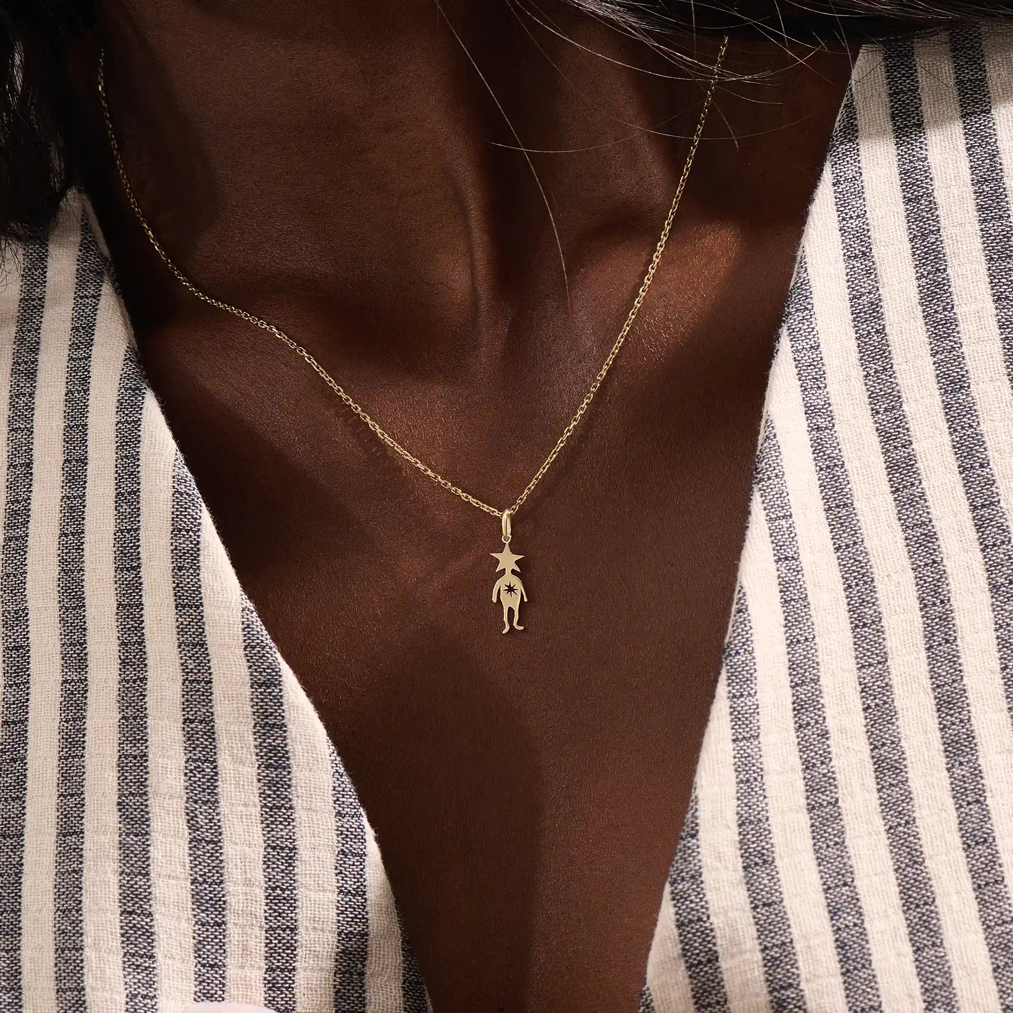Model wears a 14k gold pendant necklace with a star head charm, perfect for little boys. A delicate and meaningful piece for daily wear.