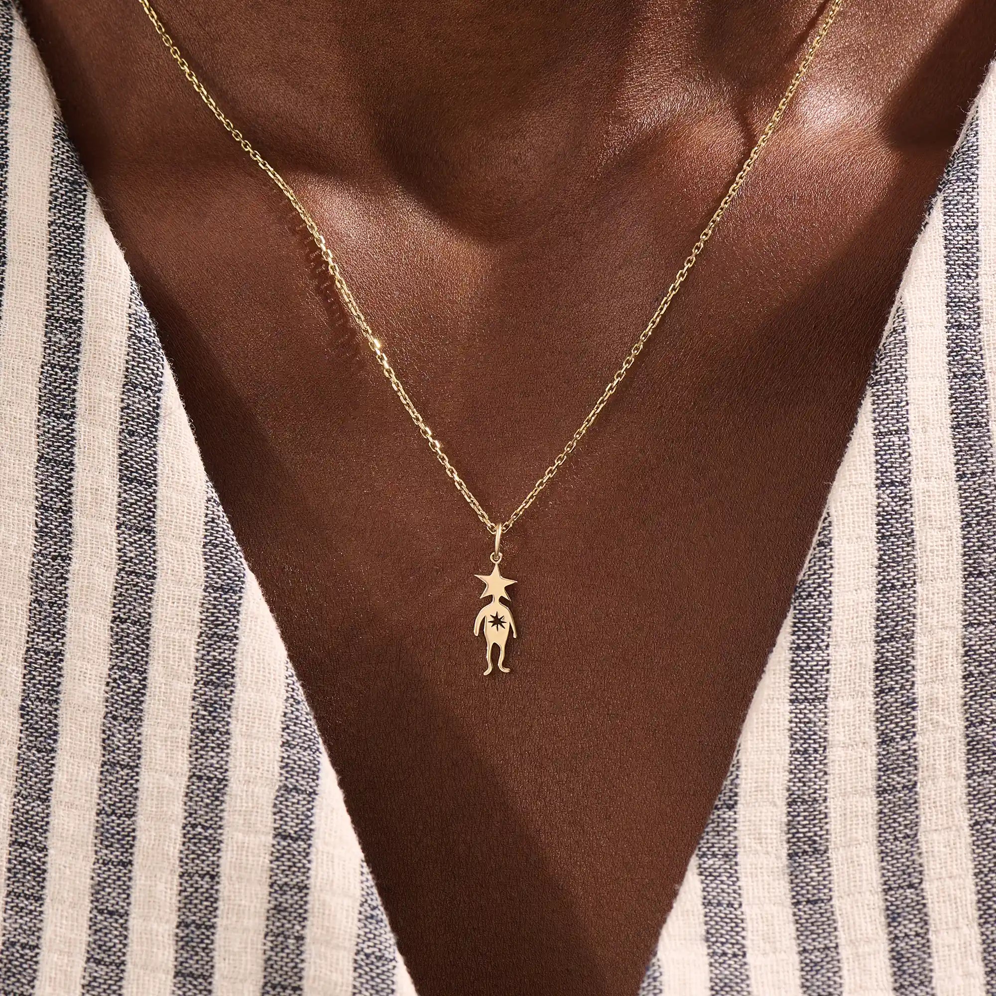 Model wears a 14k gold pendant necklace with a star head charm, perfect for little boys. A delicate and meaningful piece for daily wear.