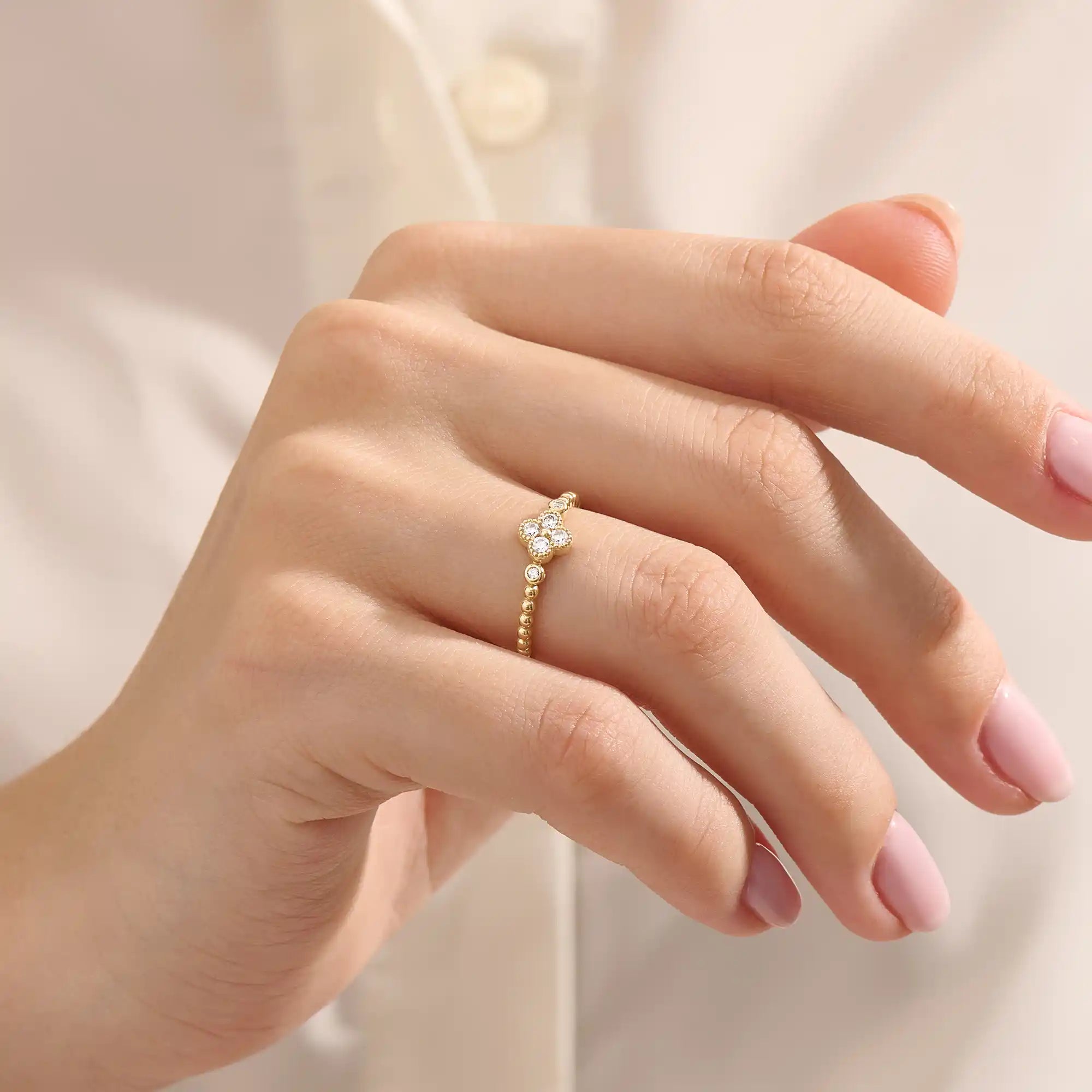 Model wears a 14k gold pinky signet ring featuring a clover-shaped moissanite and textured beaded band. Elegant and meaningful everyday jewelry.