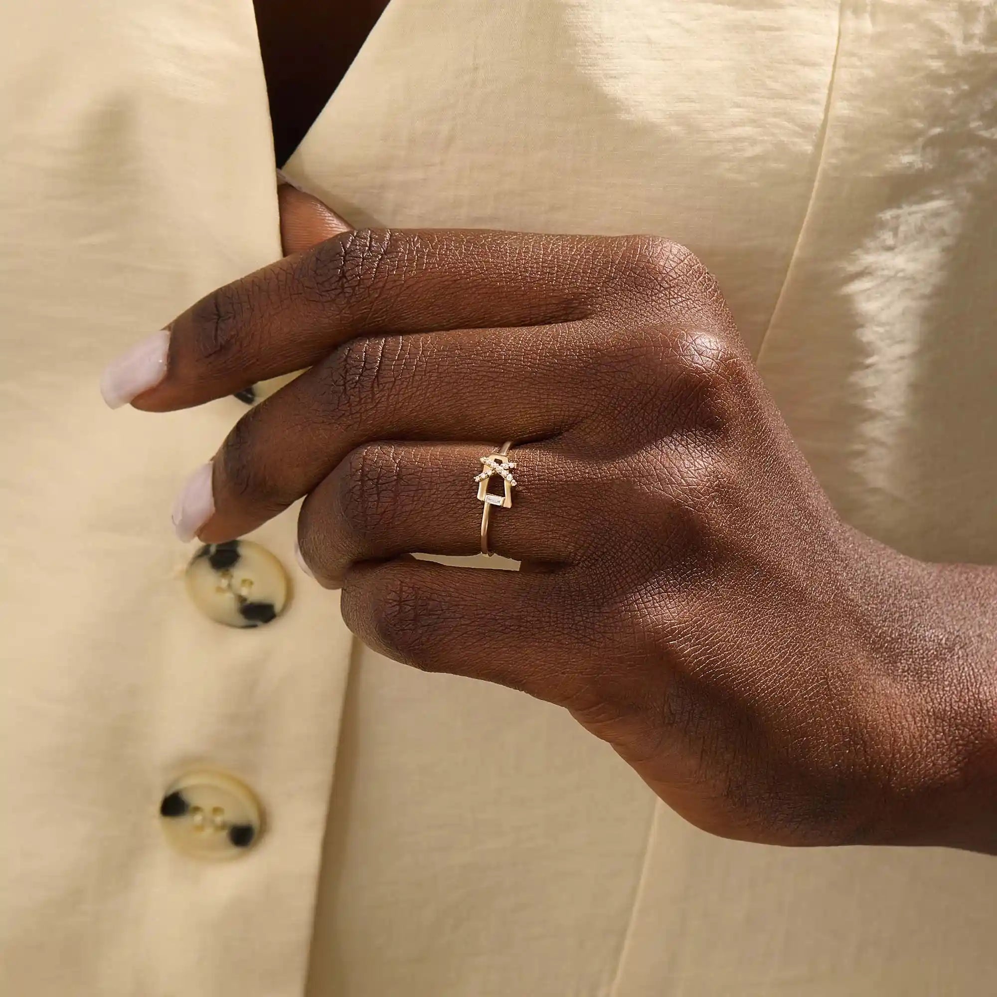 Model wears a 14k gold pinky signet ring featuring pavé moissanites in a geometric pattern. Stylish and distinctive jewelry for everyday wear.