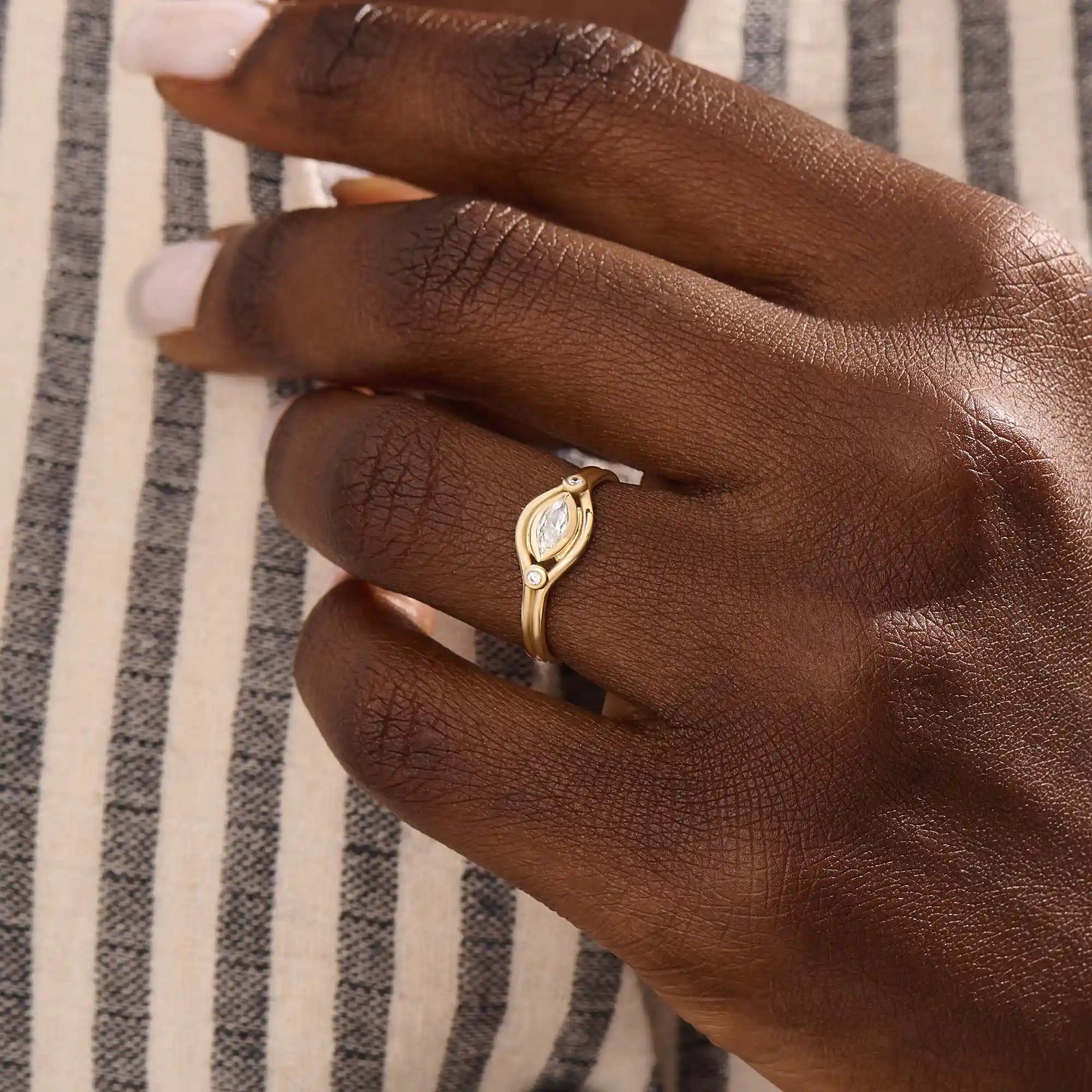 Model wears a 14k gold pinky signet ring with a marquise moissanite bezel-set evil eye motif. A unique and meaningful accessory for everyday wear.