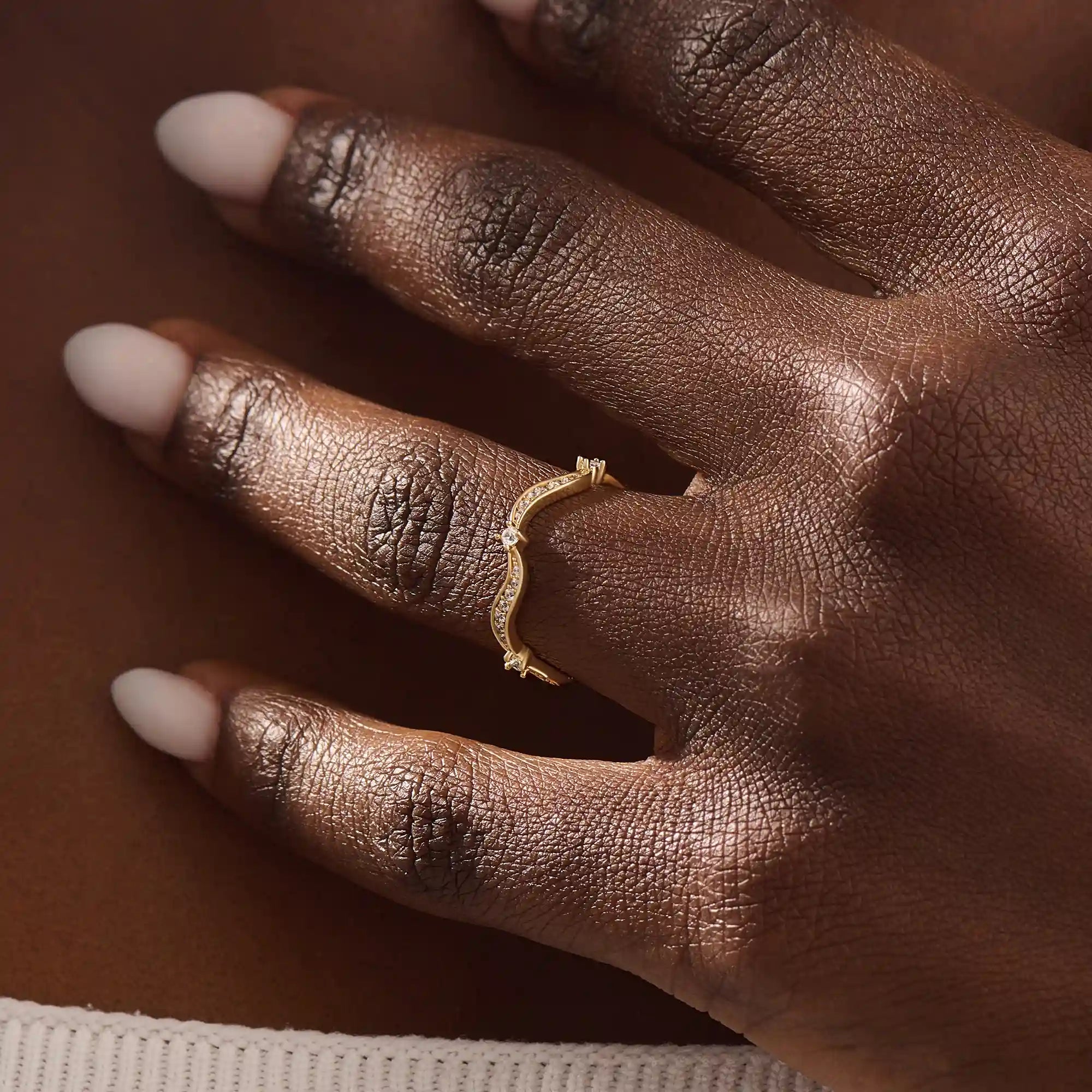 Model wears a 14k gold stacking ring with a wavy ups and downs design. Ideal for stacking or wearing solo with subtle texture.
