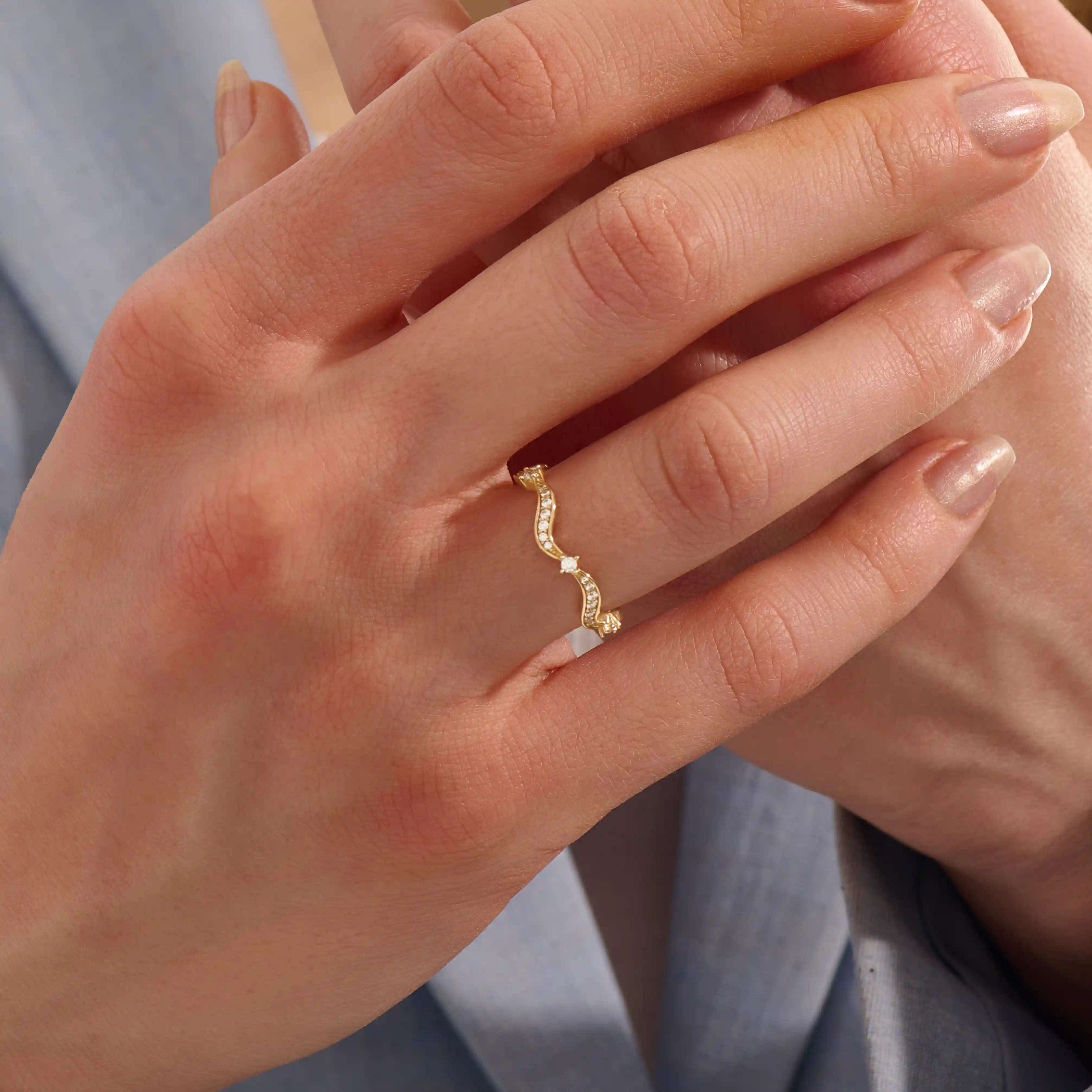 Model wears a 14k gold stacking ring with a wavy ups and downs design. Ideal for stacking or wearing solo with subtle texture.