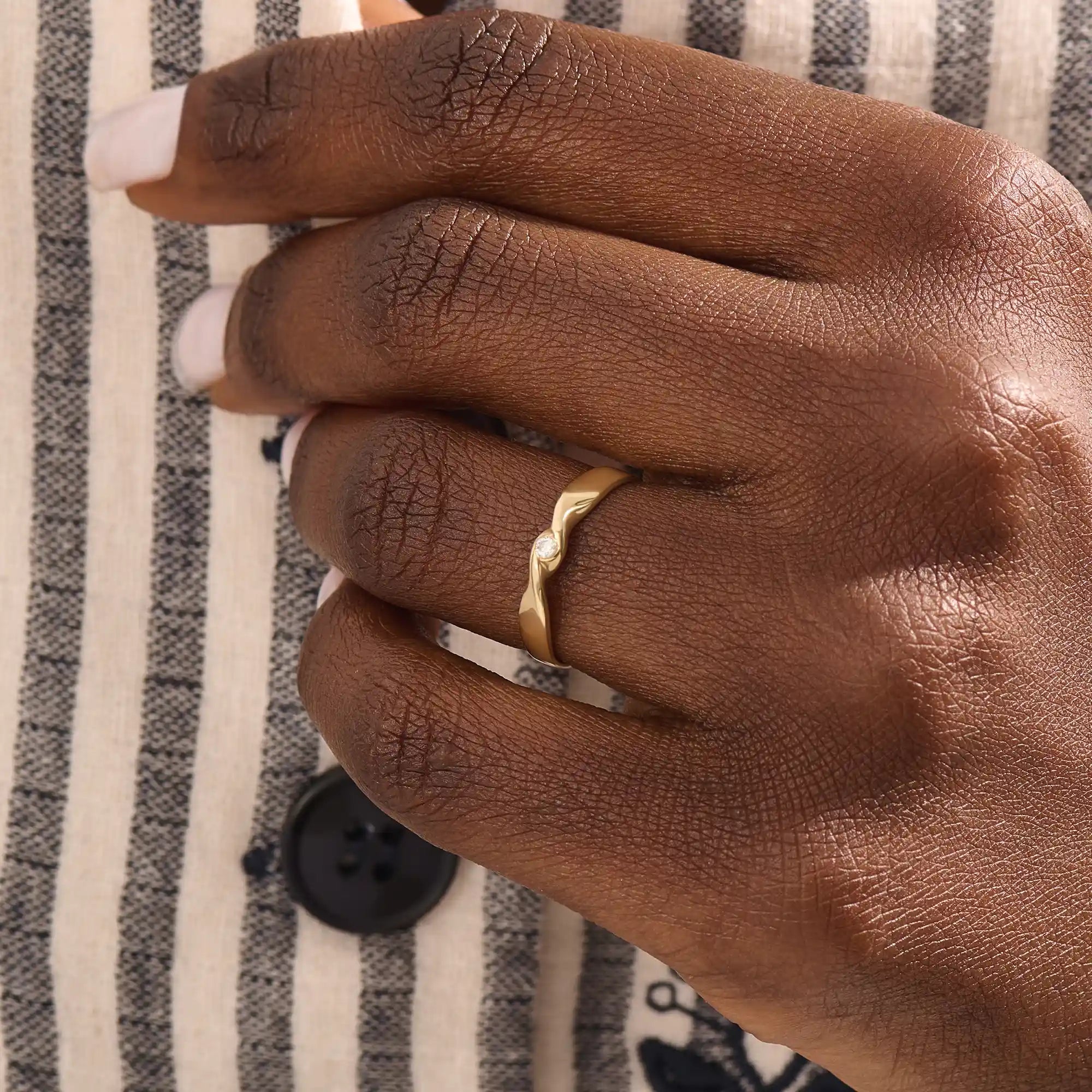 Model wears a 14k gold twisted band promise ring featuring a single bezel-set moissanite. A sleek and stylish symbol of commitment.