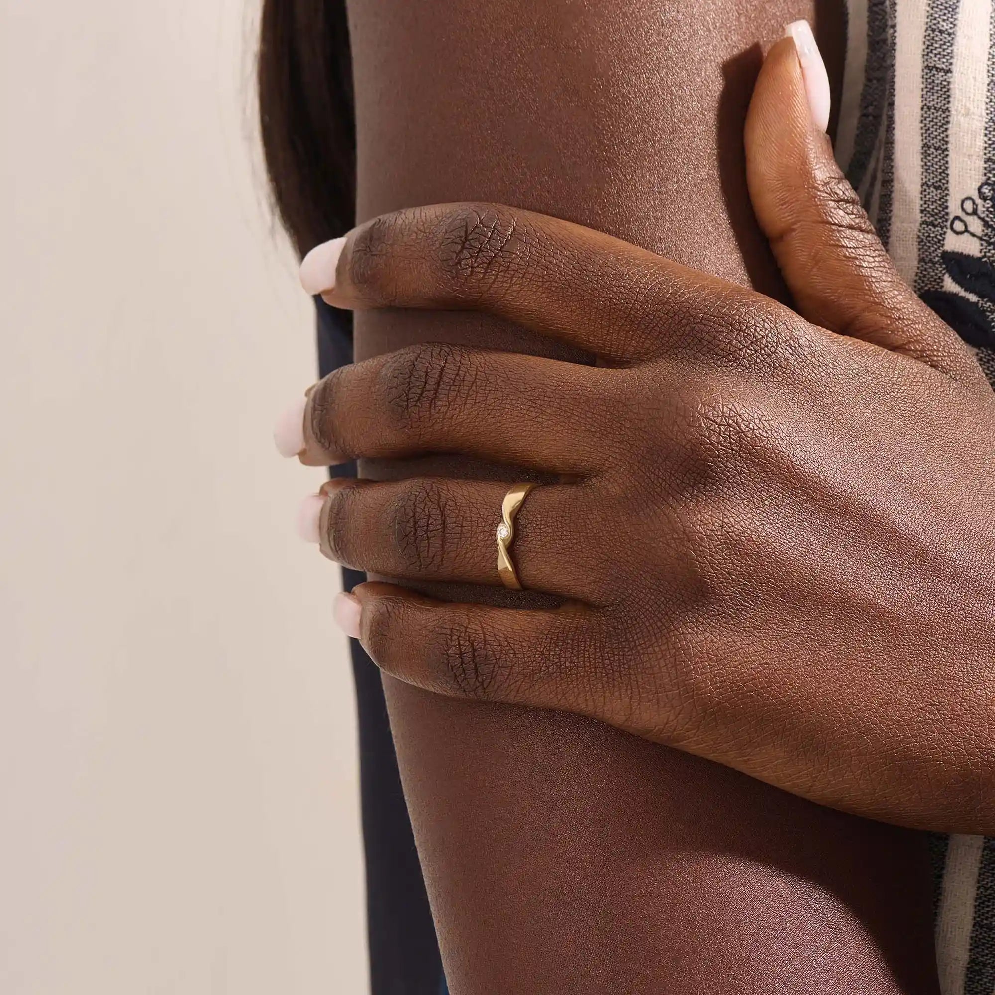 Model wears a 14k gold twisted band promise ring featuring a single bezel-set moissanite. A sleek and stylish symbol of commitment.