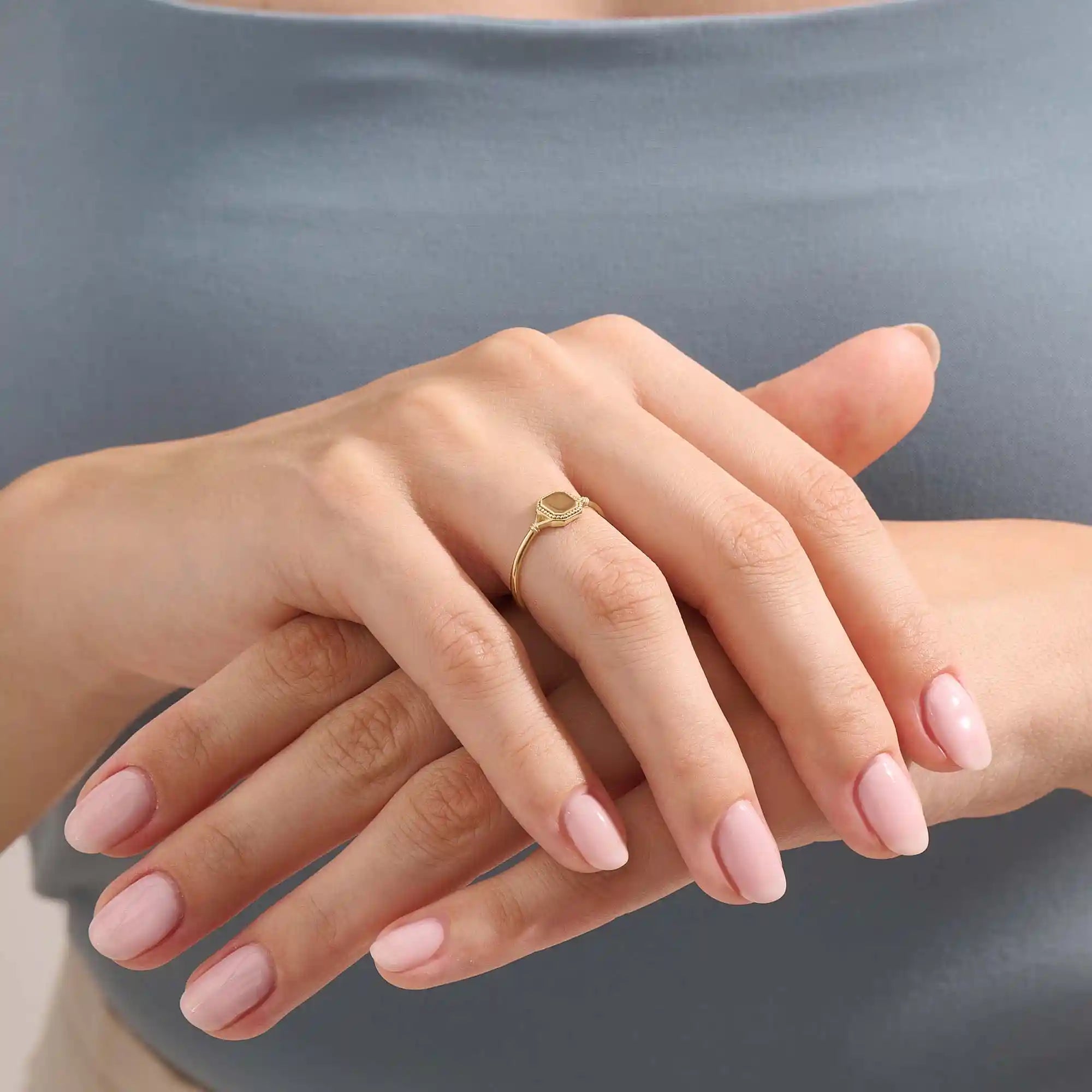 Model wears a 14k gold vintage square signet ring featuring intricate design elements. A bold and refined accessory for modern style.