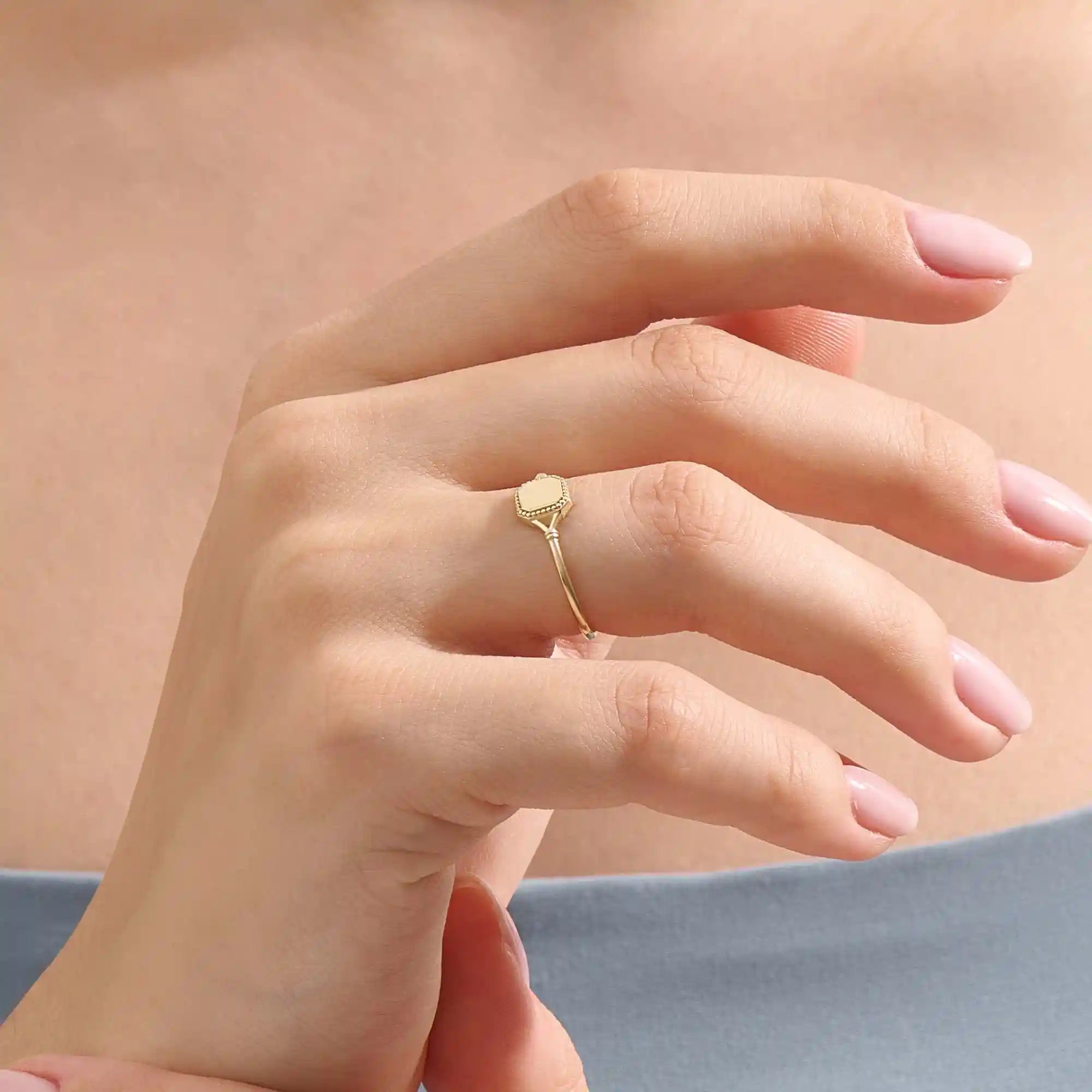 Model wears a 14k gold vintage square signet ring featuring intricate design elements. A bold and refined accessory for modern style.