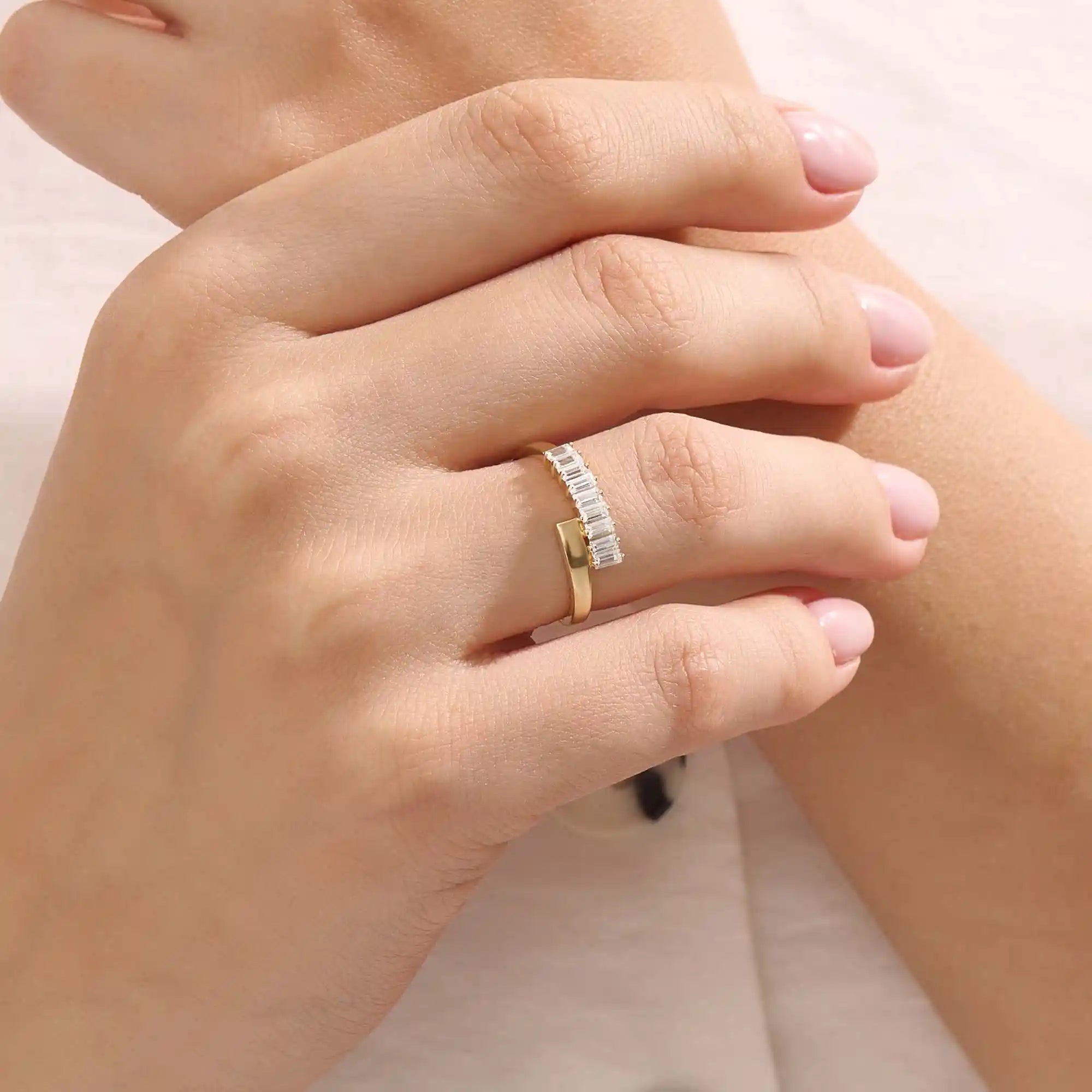 Model wears a 14k gold wrap-around spiral statement ring featuring baguette half eternity moissanites. Bold and stylish everyday accessory.