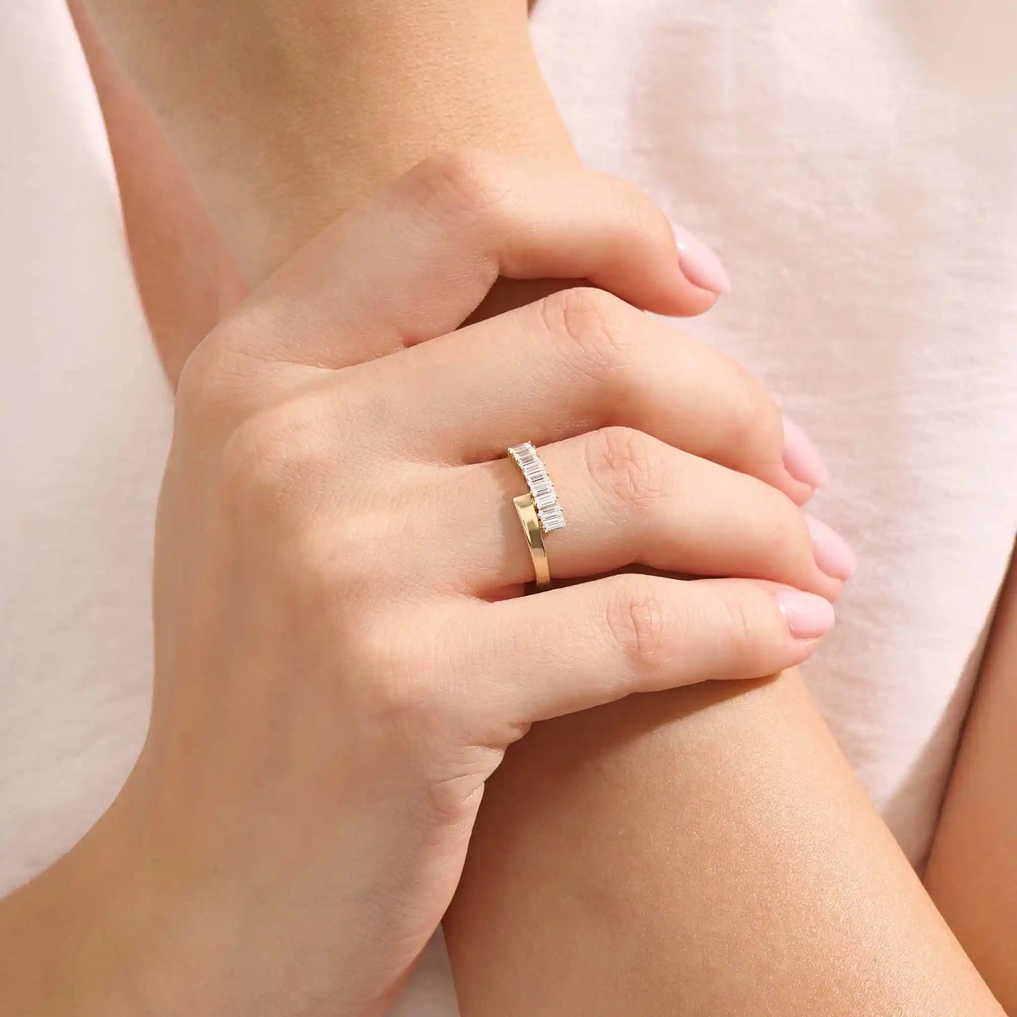 Model wears a 14k gold wrap-around spiral statement ring featuring baguette half eternity moissanites. Bold and stylish everyday accessory.