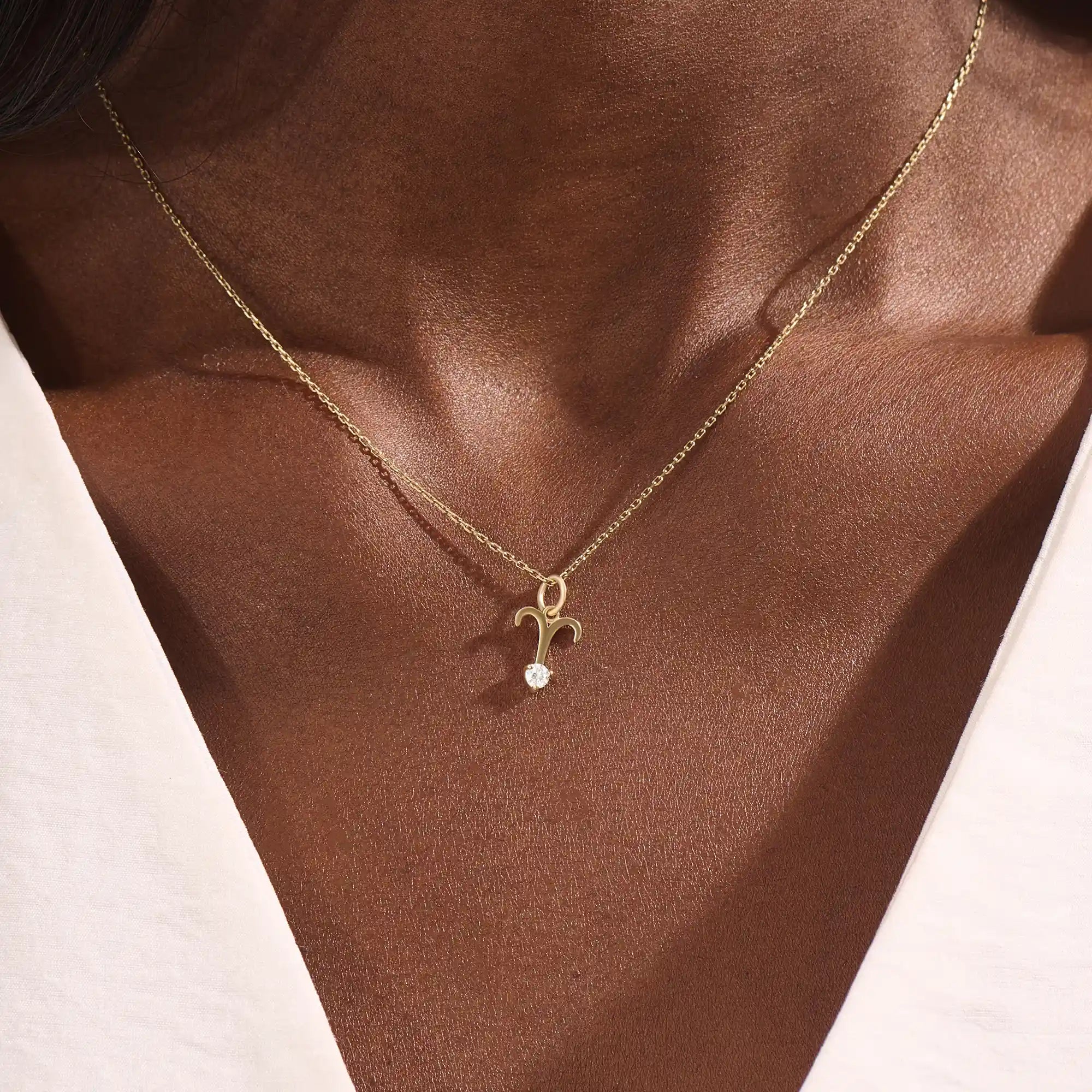 Model wears a 14k solid gold Aries zodiac symbol pendant necklace with clear moissanite, perfect for Aries astrology lovers.