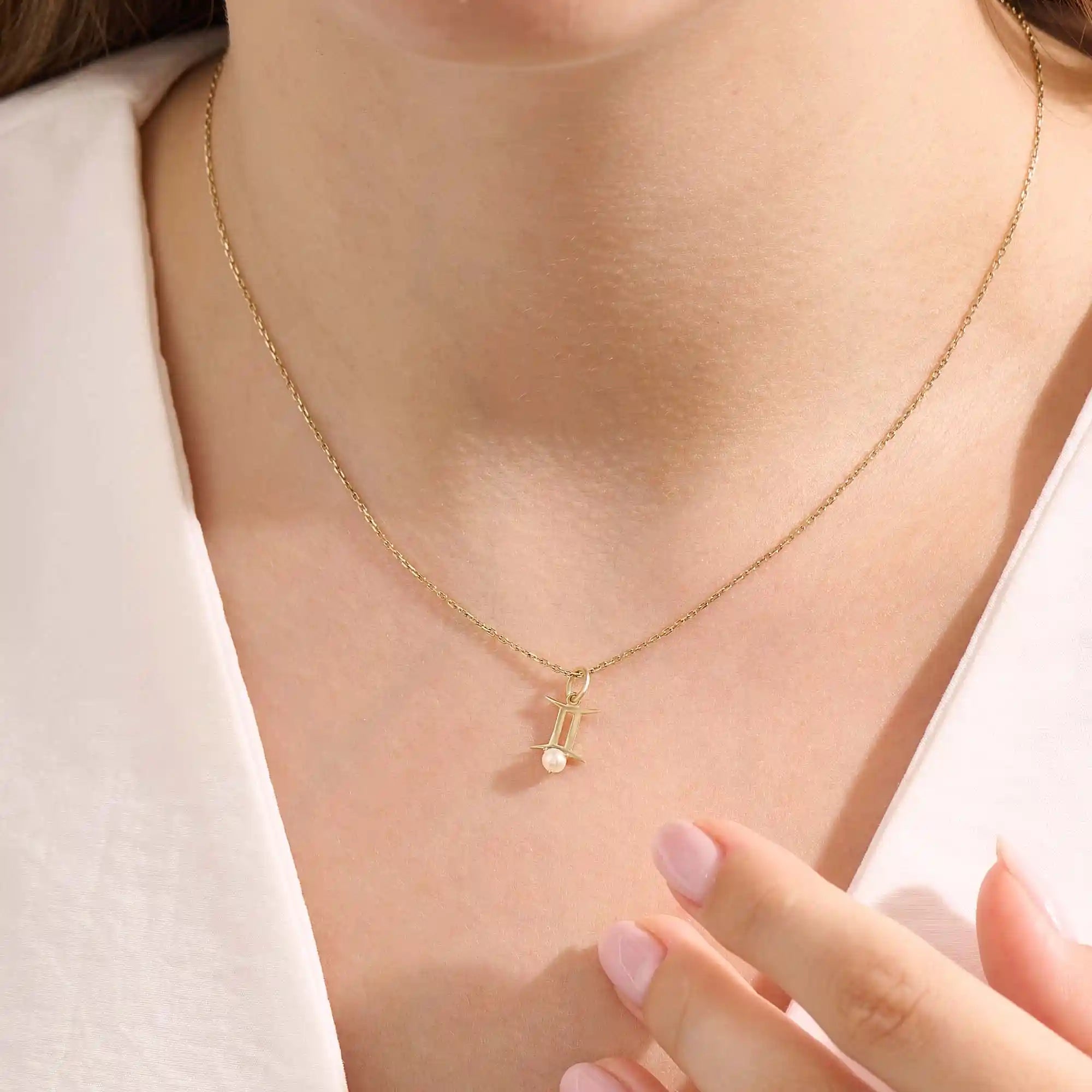 Model wears a 14k solid gold Gemini zodiac symbol pendant necklace with a natural pearl, perfect for astrology lovers.
