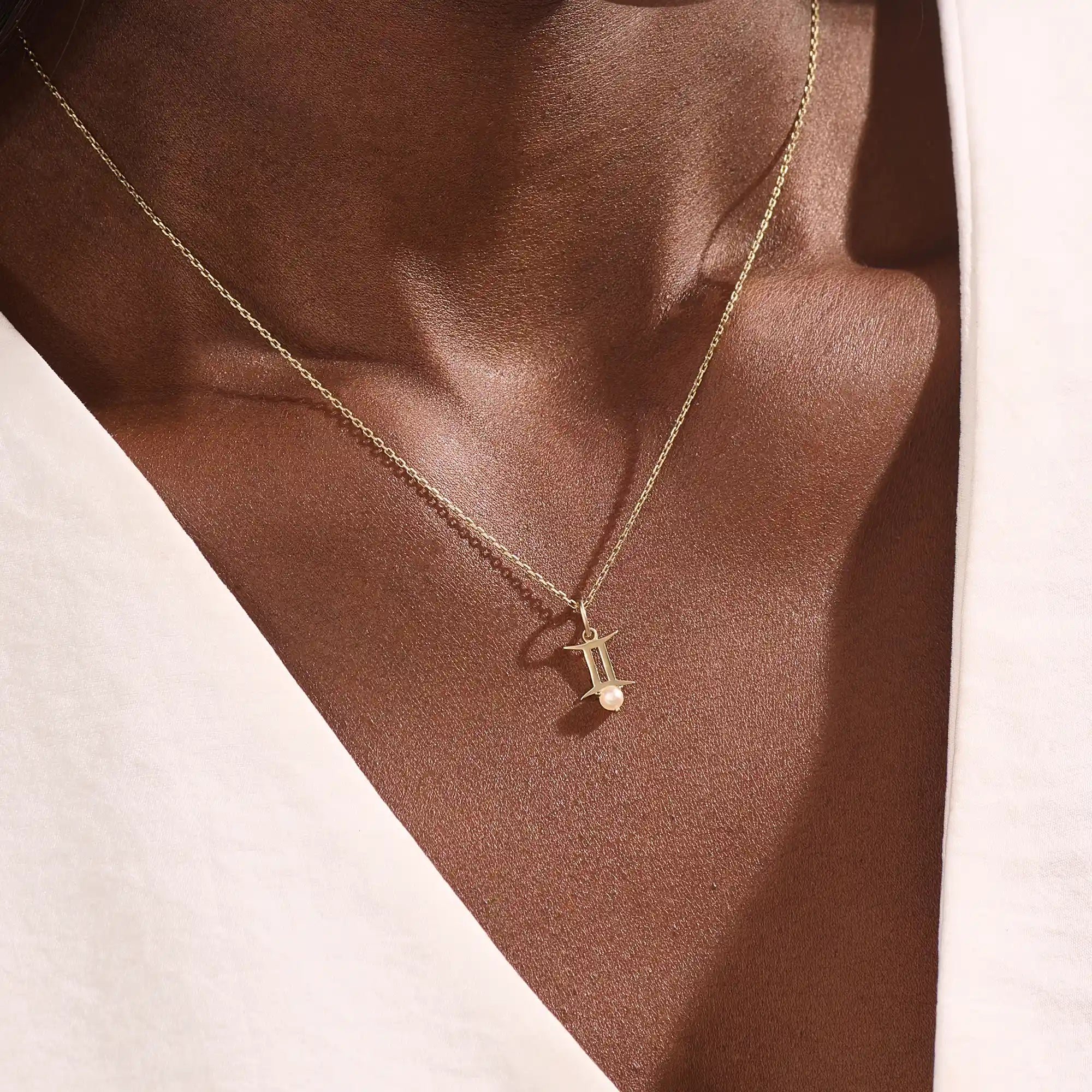 Model wears a 14k solid gold Gemini zodiac symbol pendant necklace with a natural pearl, perfect for astrology lovers.