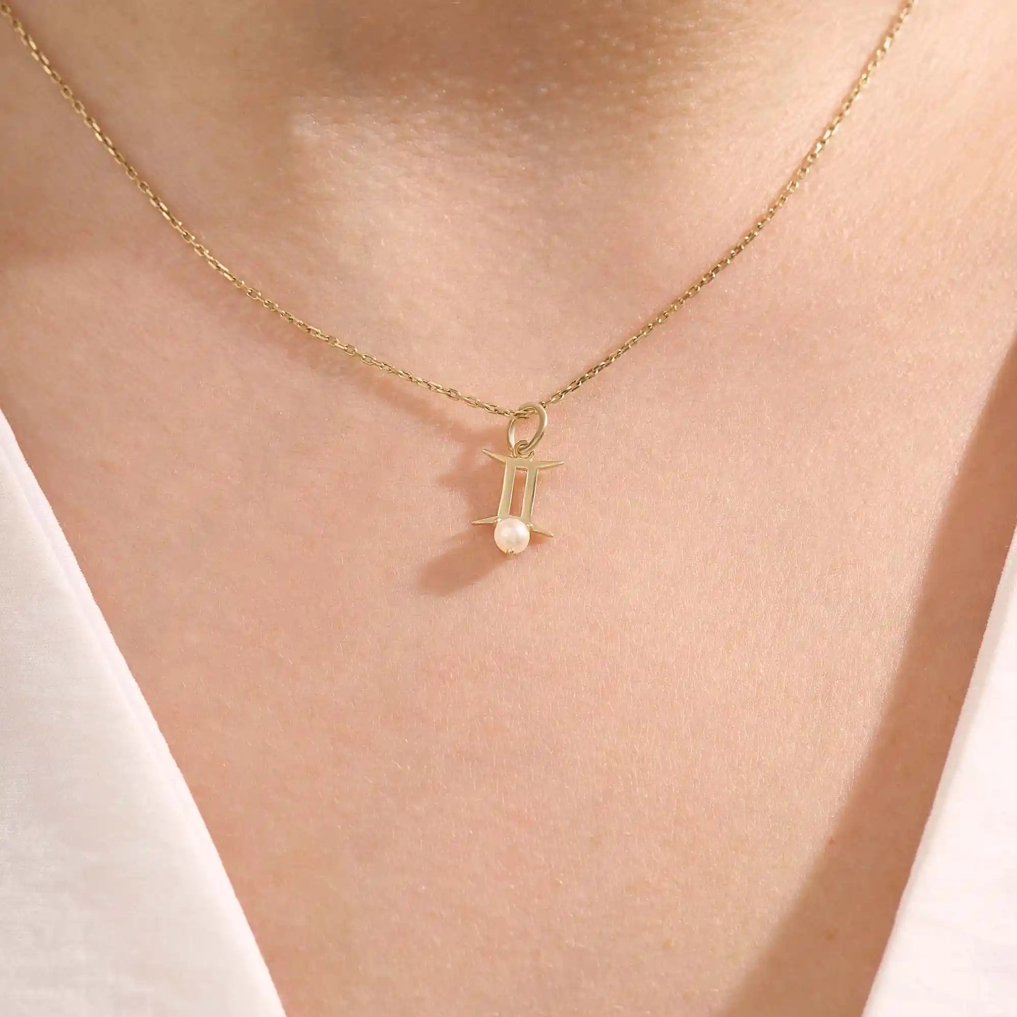 Model wears a 14k solid gold Gemini zodiac symbol pendant necklace with a natural pearl, perfect for astrology lovers.
