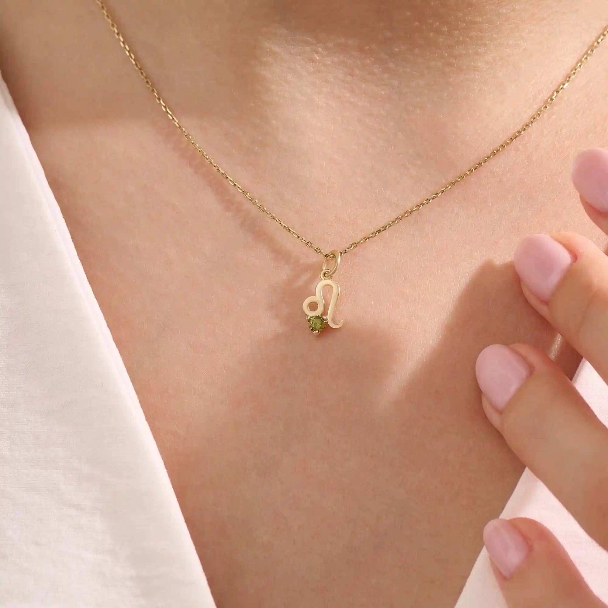 Model wears a 14k solid gold Leo zodiac symbol pendant necklace with green peridot, perfect for Leo zodiac birthdays.