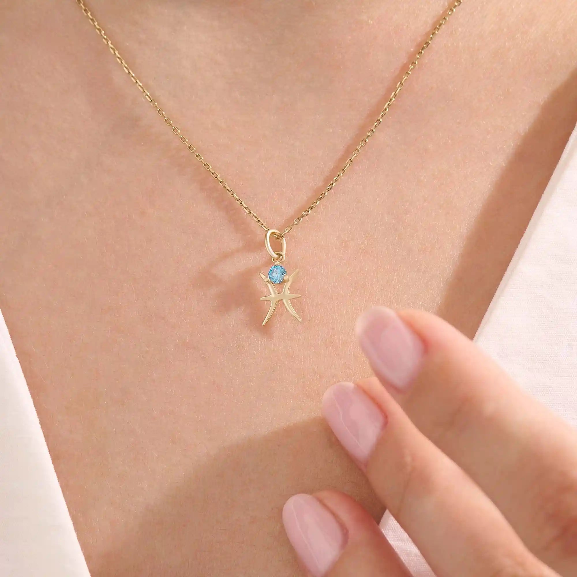 Model wears a 14k solid gold Pisces zodiac symbol pendant necklace with aquamarine, perfect for Pisces zodiac birthdays.