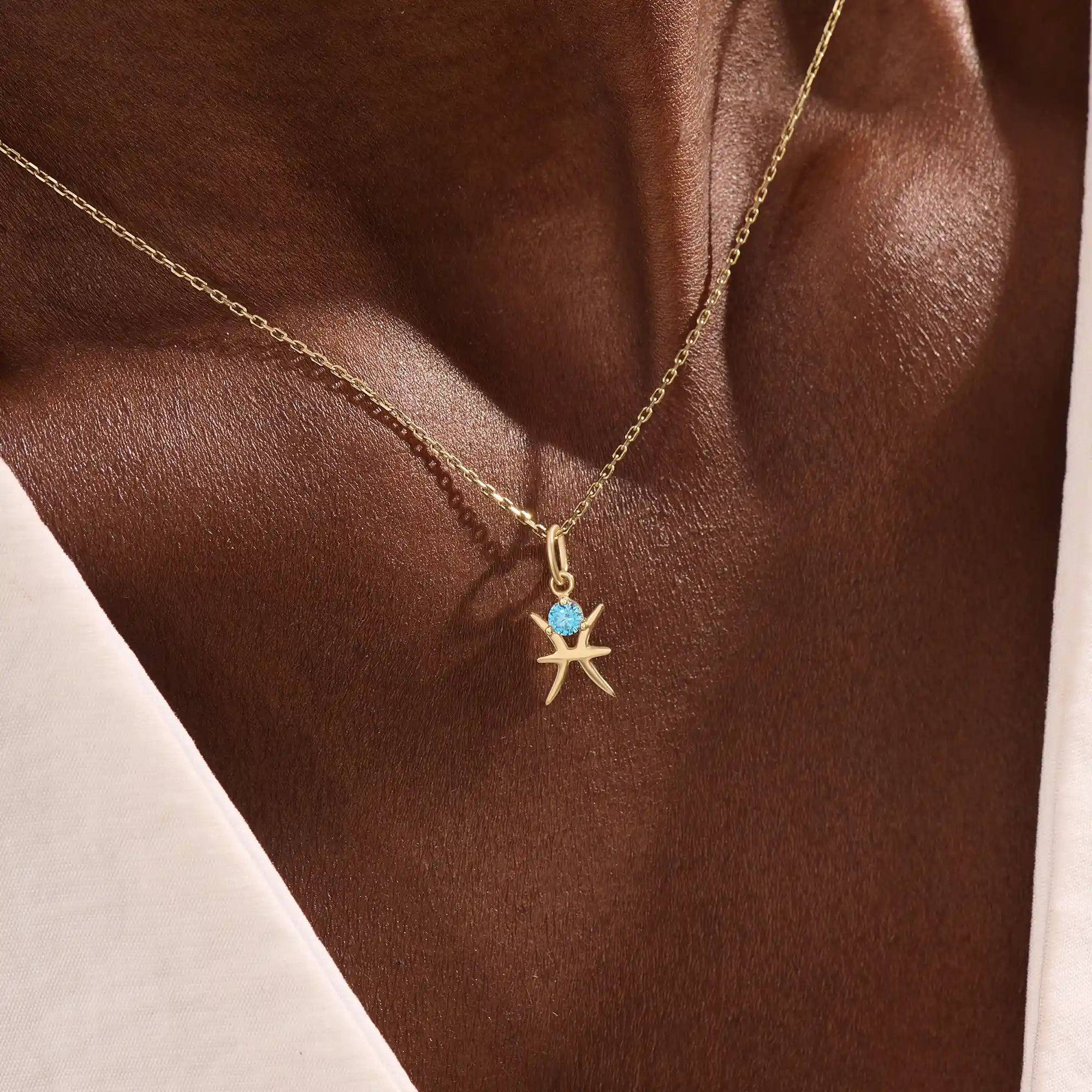 Model wears a 14k solid gold Pisces zodiac symbol pendant necklace with aquamarine, perfect for Pisces zodiac birthdays.