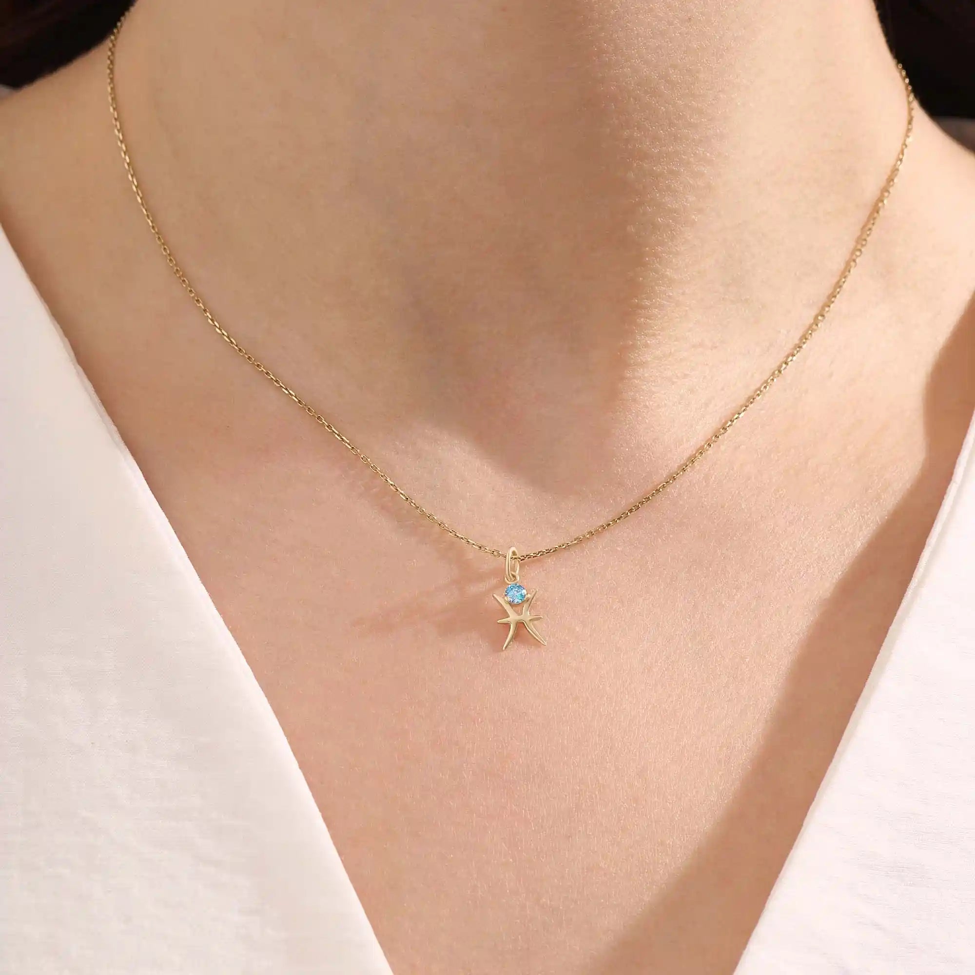Model wears a 14k solid gold Pisces zodiac symbol pendant necklace with aquamarine, perfect for Pisces zodiac birthdays.