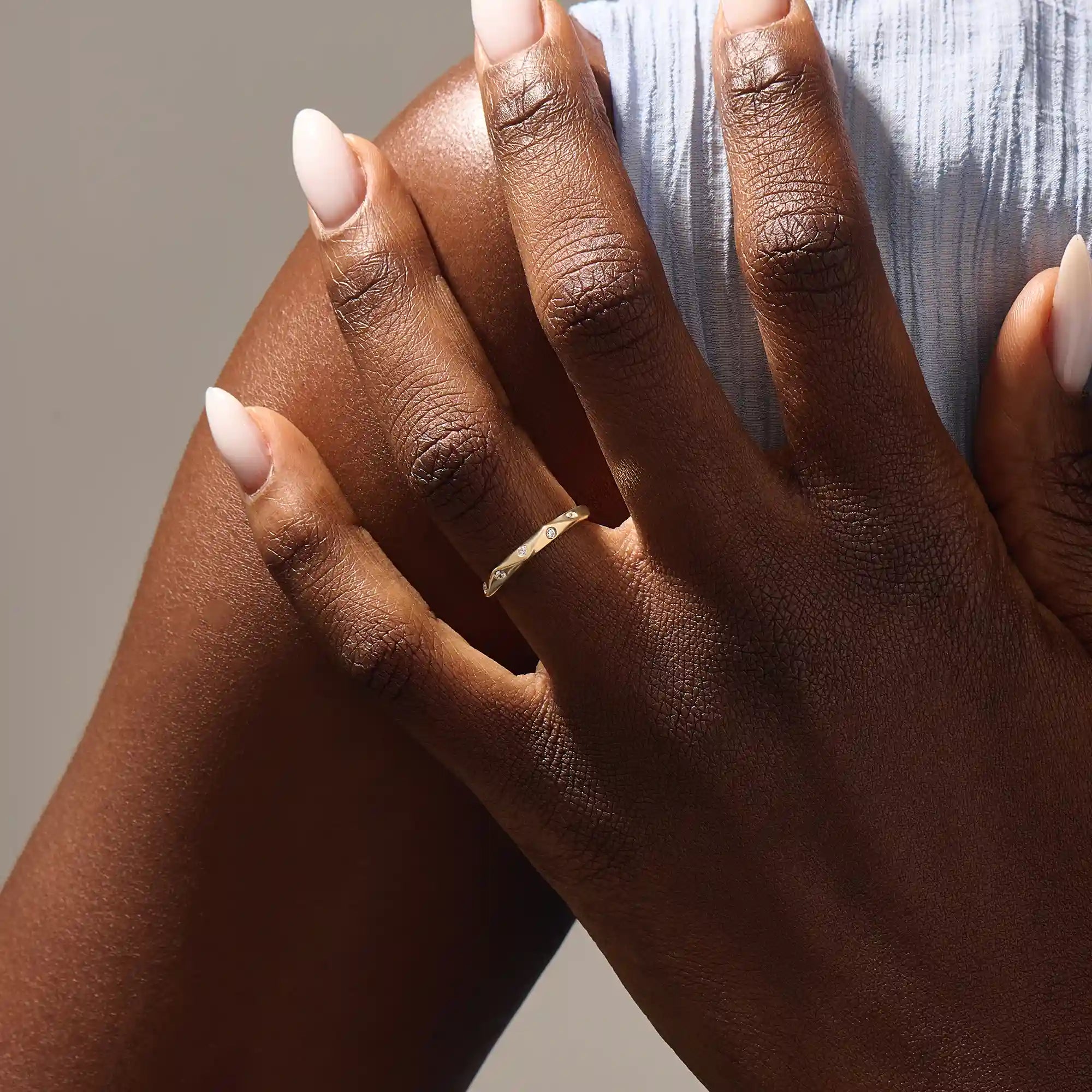 Model wears a 14k solid gold faceted band wedding ring featuring tiny moissanites. Elegant and versatile style for stacking or bridal jewelry.
