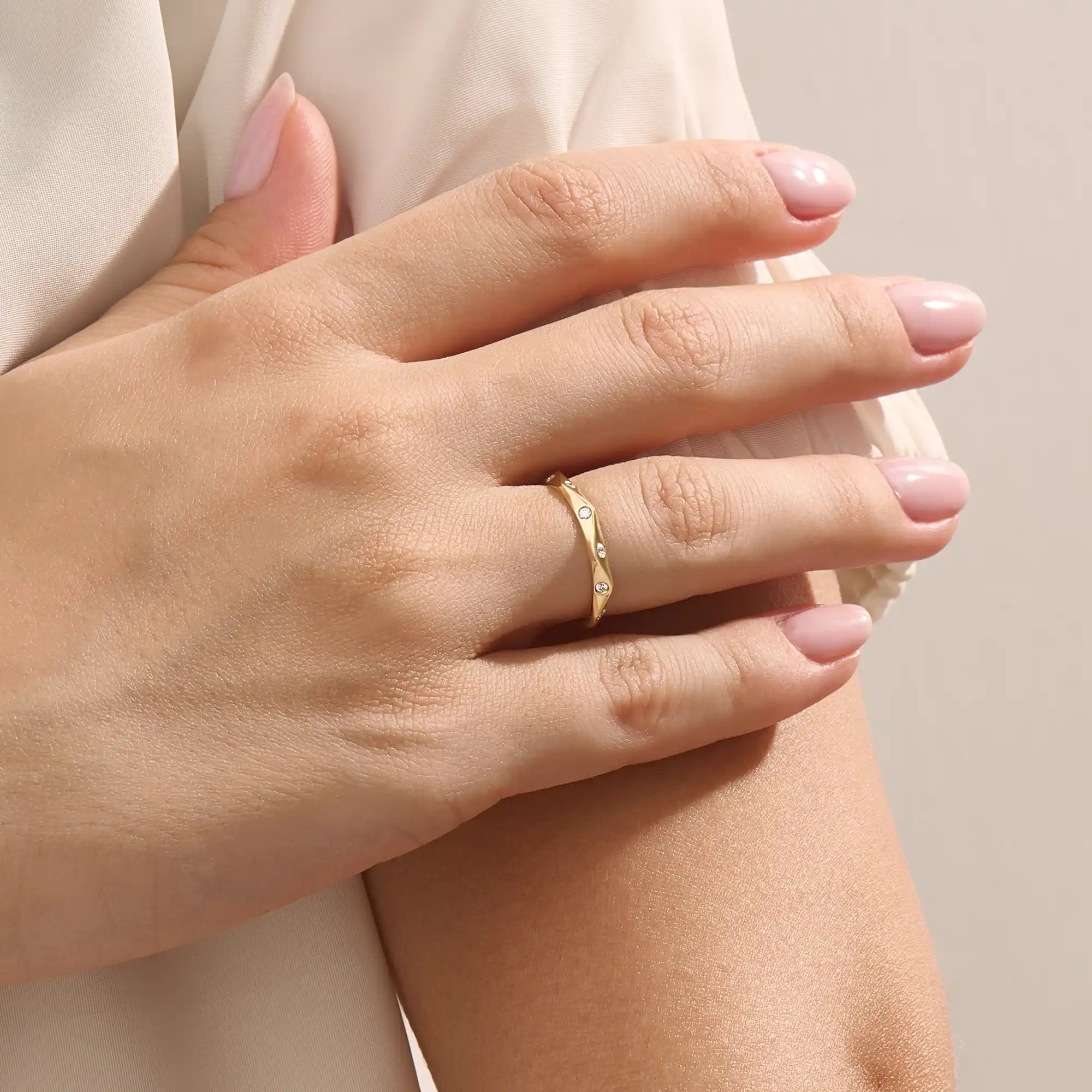Model wears a 14k solid gold faceted band wedding ring featuring tiny moissanites. Elegant and versatile style for stacking or bridal jewelry.