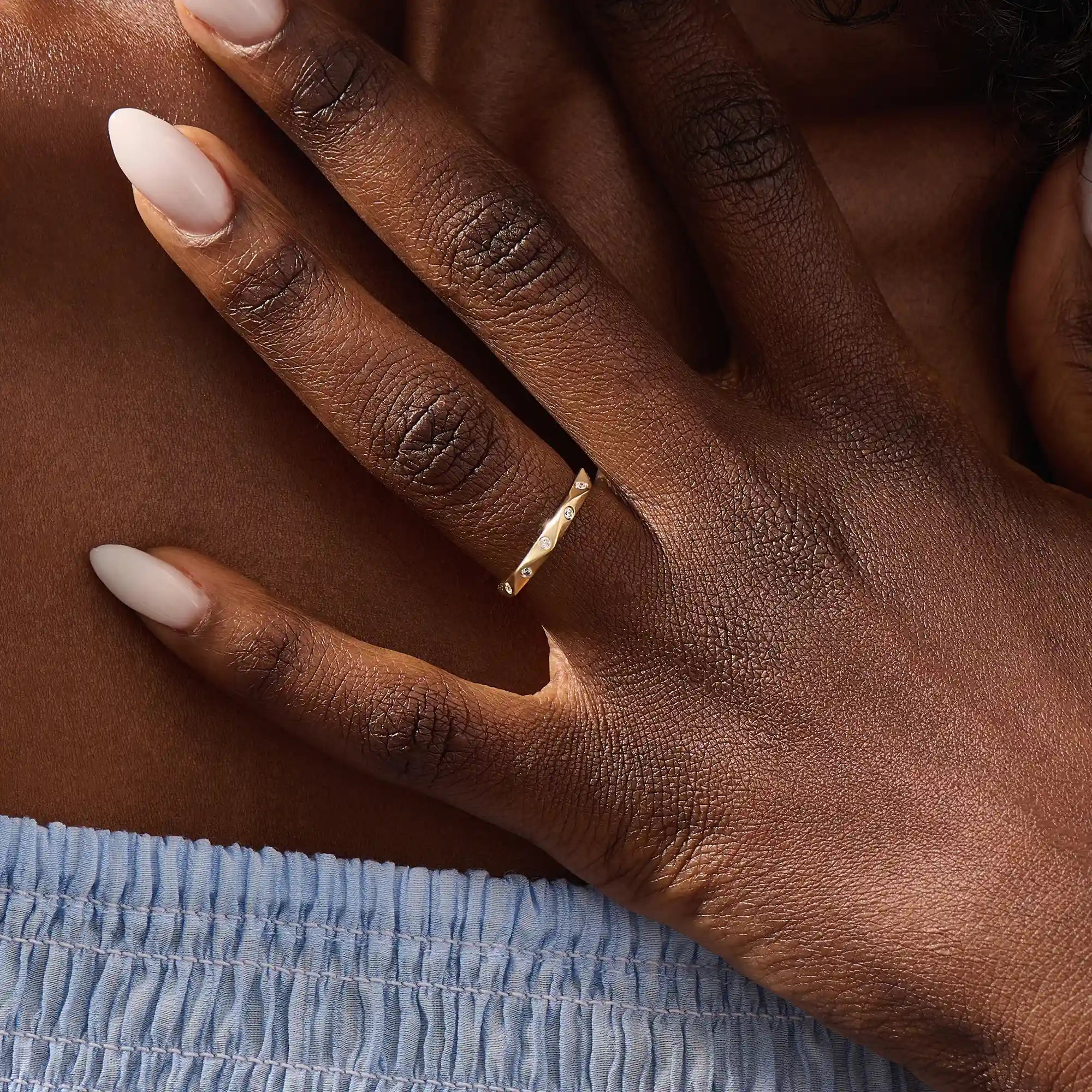 Model wears a 14k solid gold faceted band wedding ring featuring tiny moissanites. Elegant and versatile style for stacking or bridal jewelry.