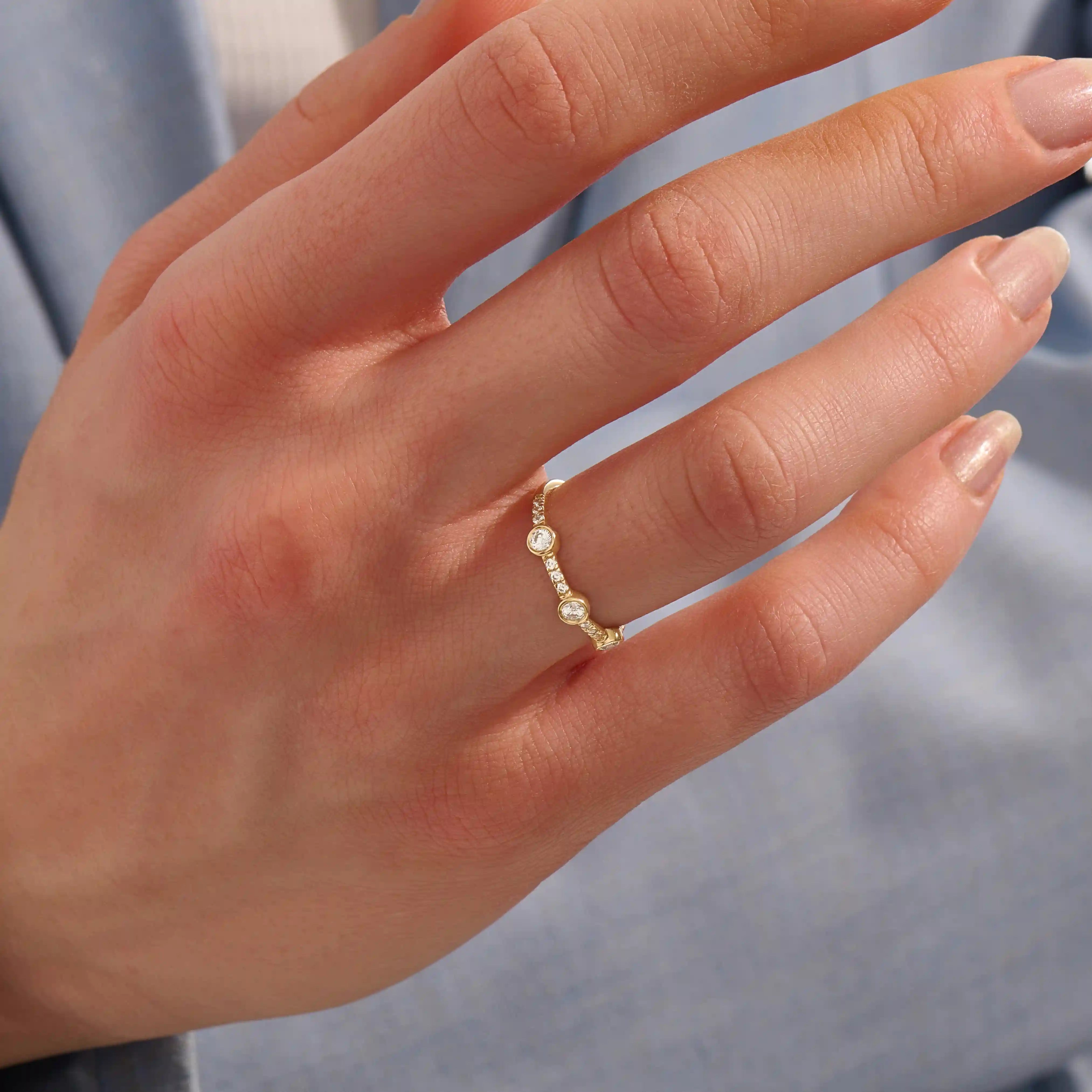 Model wears a 14k solid gold half-eternity stacking ring with three bezel moissanites. Elegant and perfect for layering.