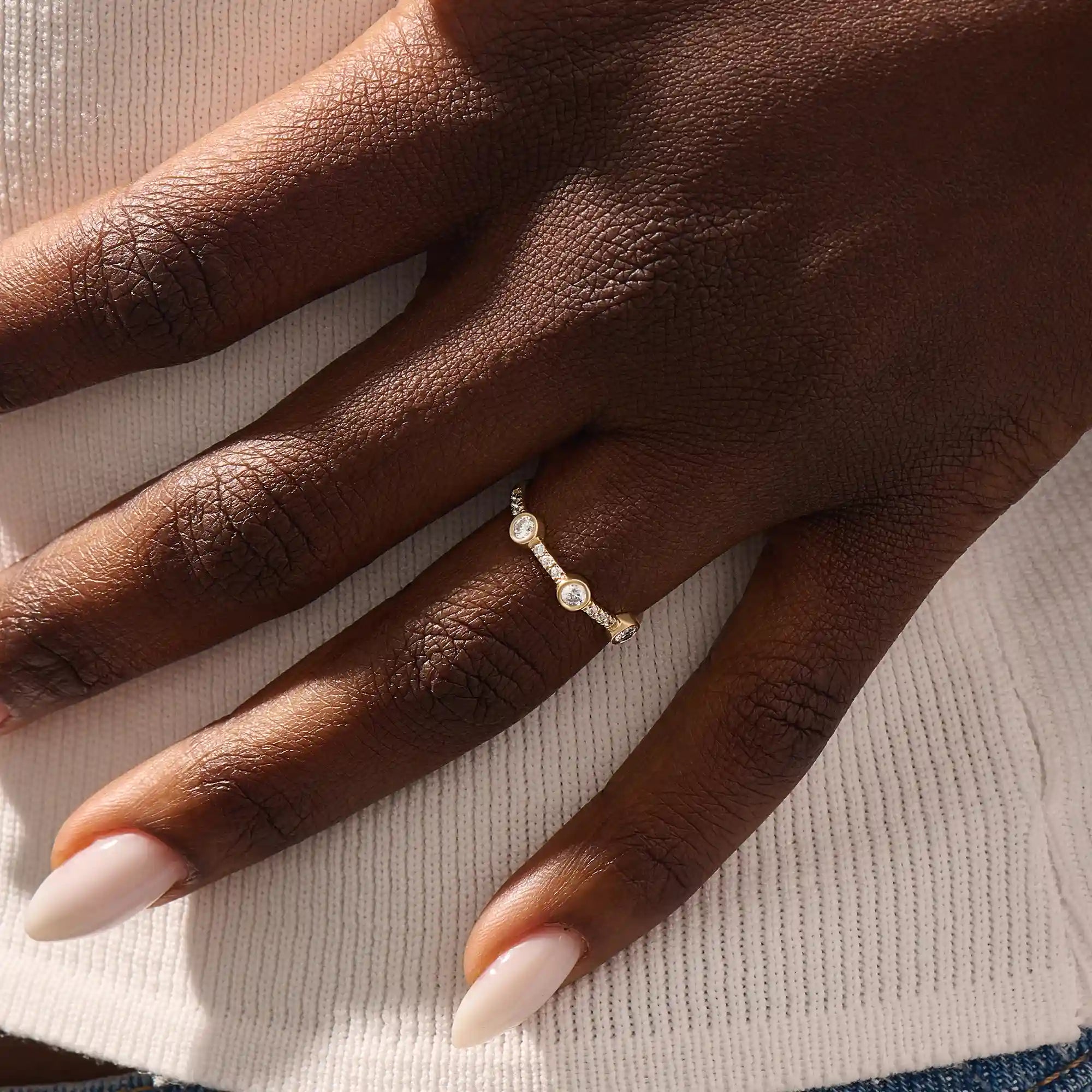 Model wears a 14k solid gold half-eternity stacking ring with three bezel moissanites. Elegant and perfect for layering.