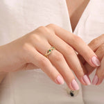 Model wears a 14k solid gold leaf vine band with a bezel-set emerald gemstone. Elegant and nature-inspired style.