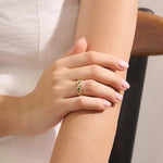 Model wears a 14k solid gold leaf vine band with a bezel-set emerald gemstone. Elegant and nature-inspired style.