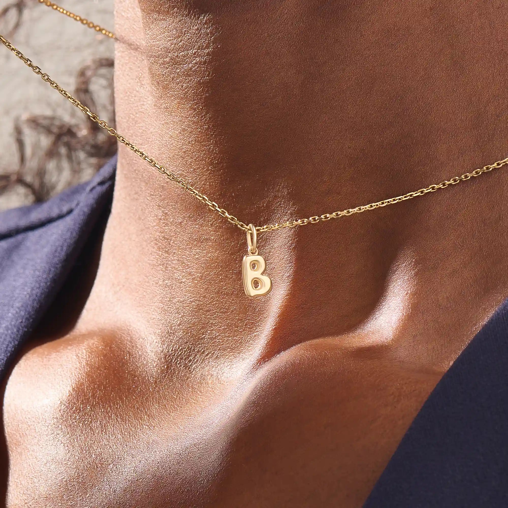 Model wears a 14k solid gold puffy letter necklace with a bold yet delicate look. The sculpted design adds a playful and personalized touch.