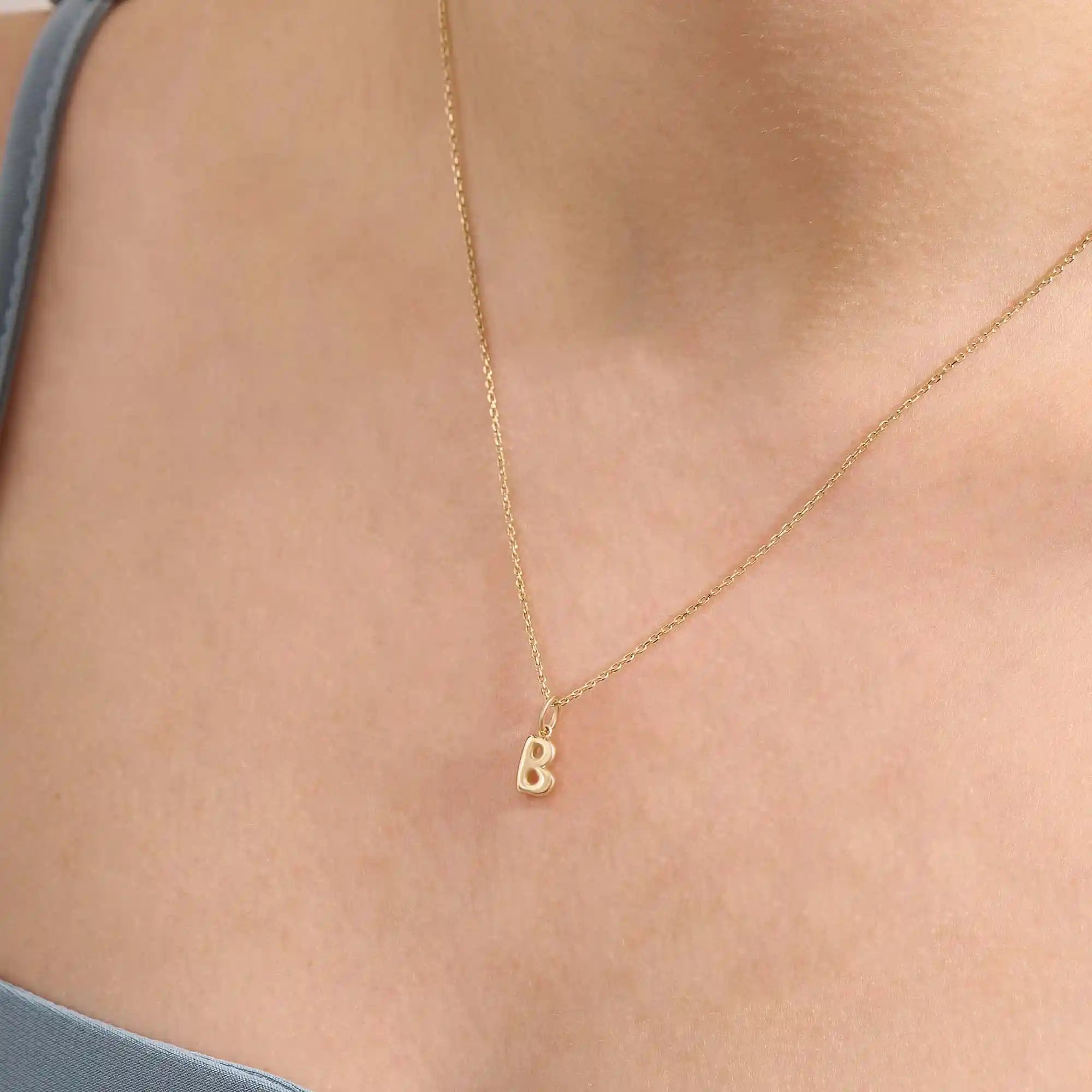 Model wears a 14k solid gold puffy letter necklace with a bold yet delicate look. The sculpted design adds a playful and personalized touch.