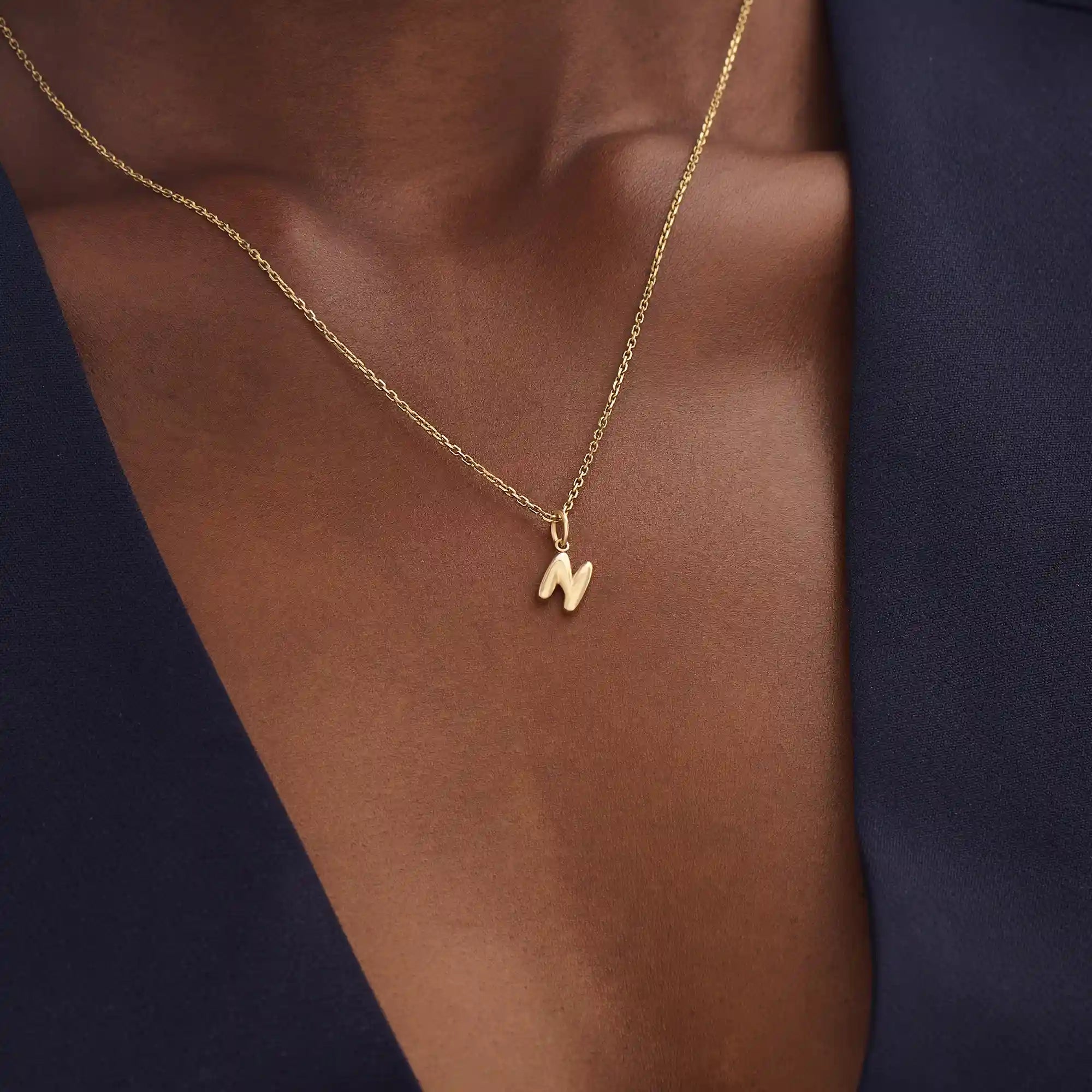 Model wears a 14k solid gold puffy letter necklace with a bold yet delicate look. The sculpted design adds a playful and personalized touch.