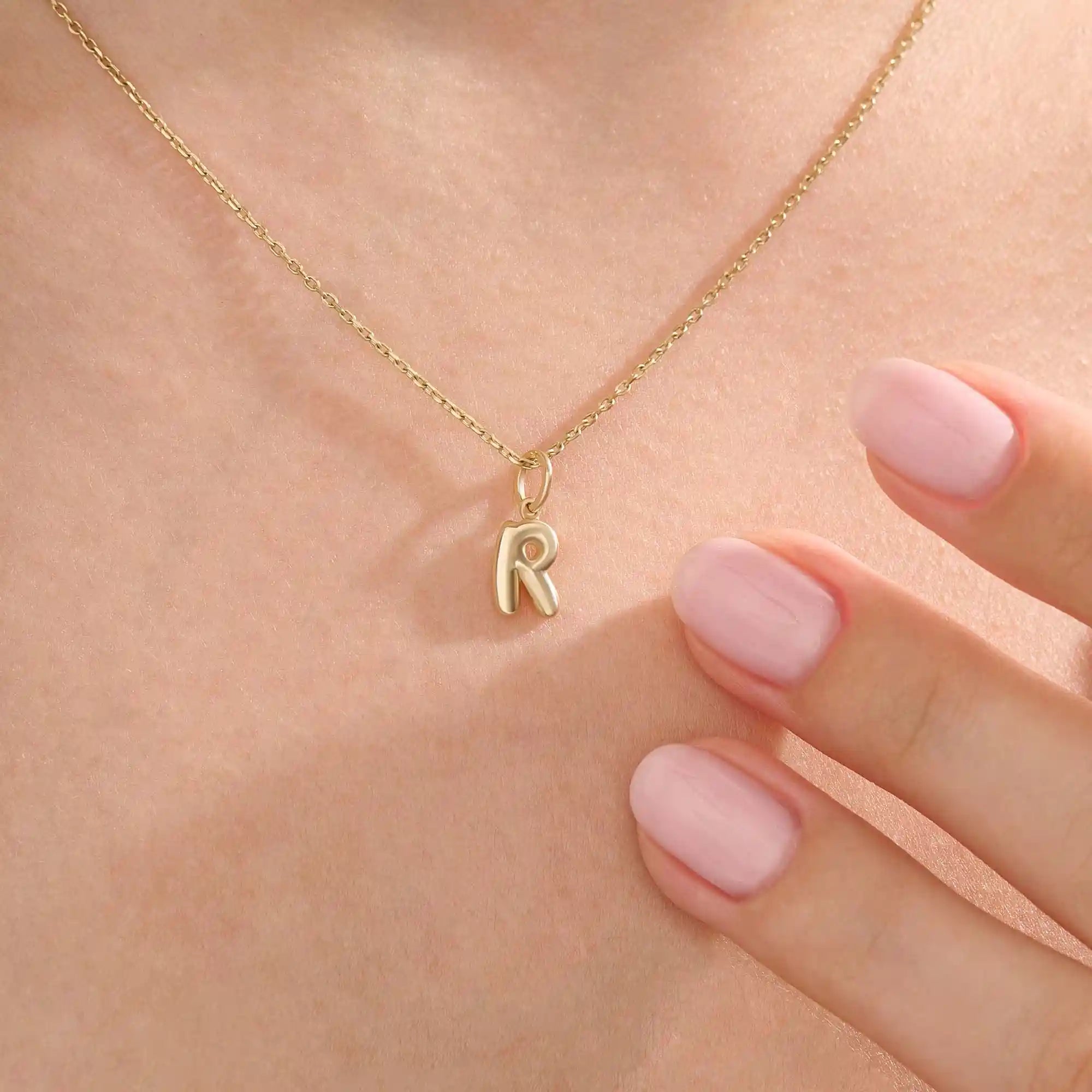 Model wears a 14k solid gold puffy letter necklace with a bold yet delicate look. The sculpted design adds a playful and personalized touch.