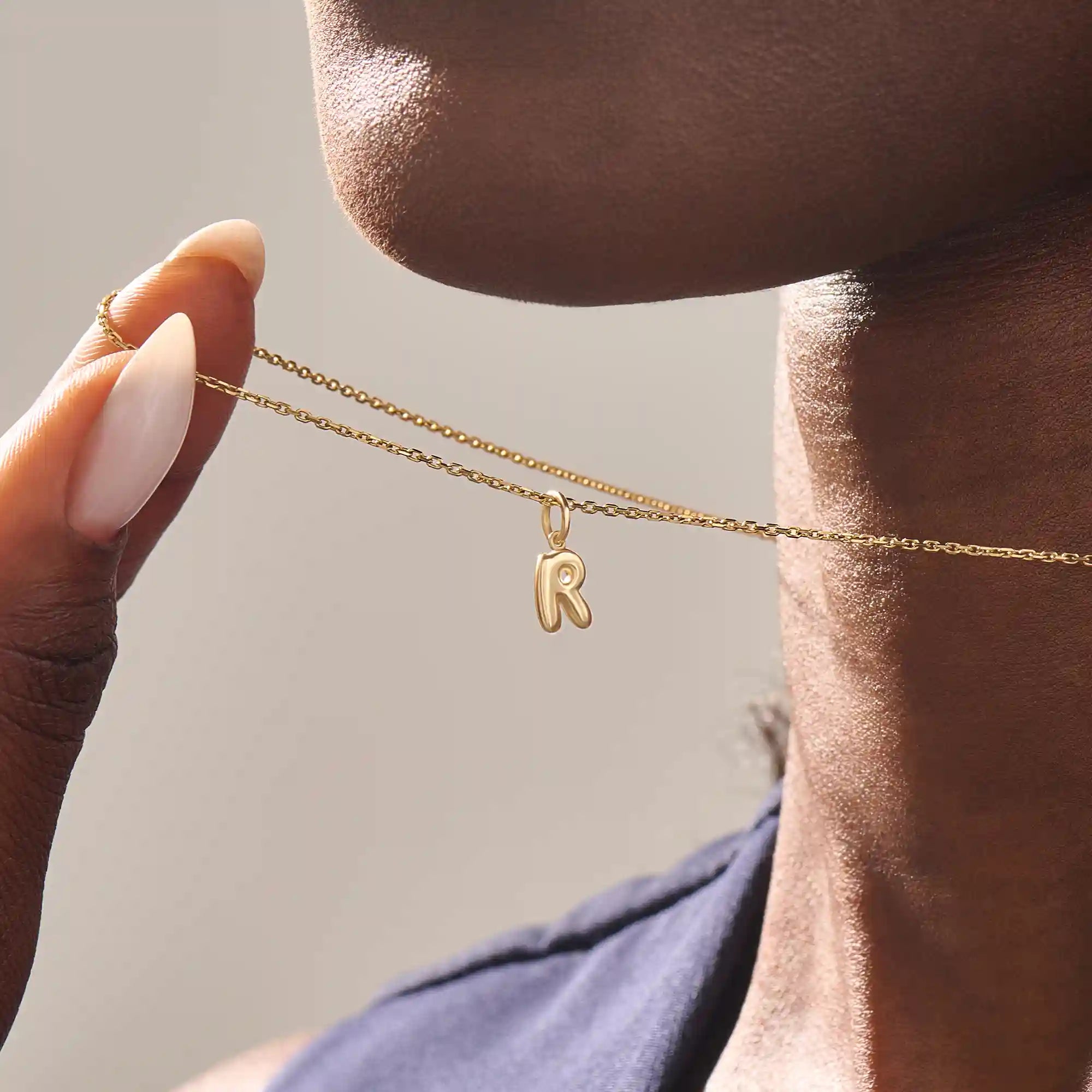 Model wears a 14k solid gold puffy letter necklace with a bold yet delicate look. The sculpted design adds a playful and personalized touch.