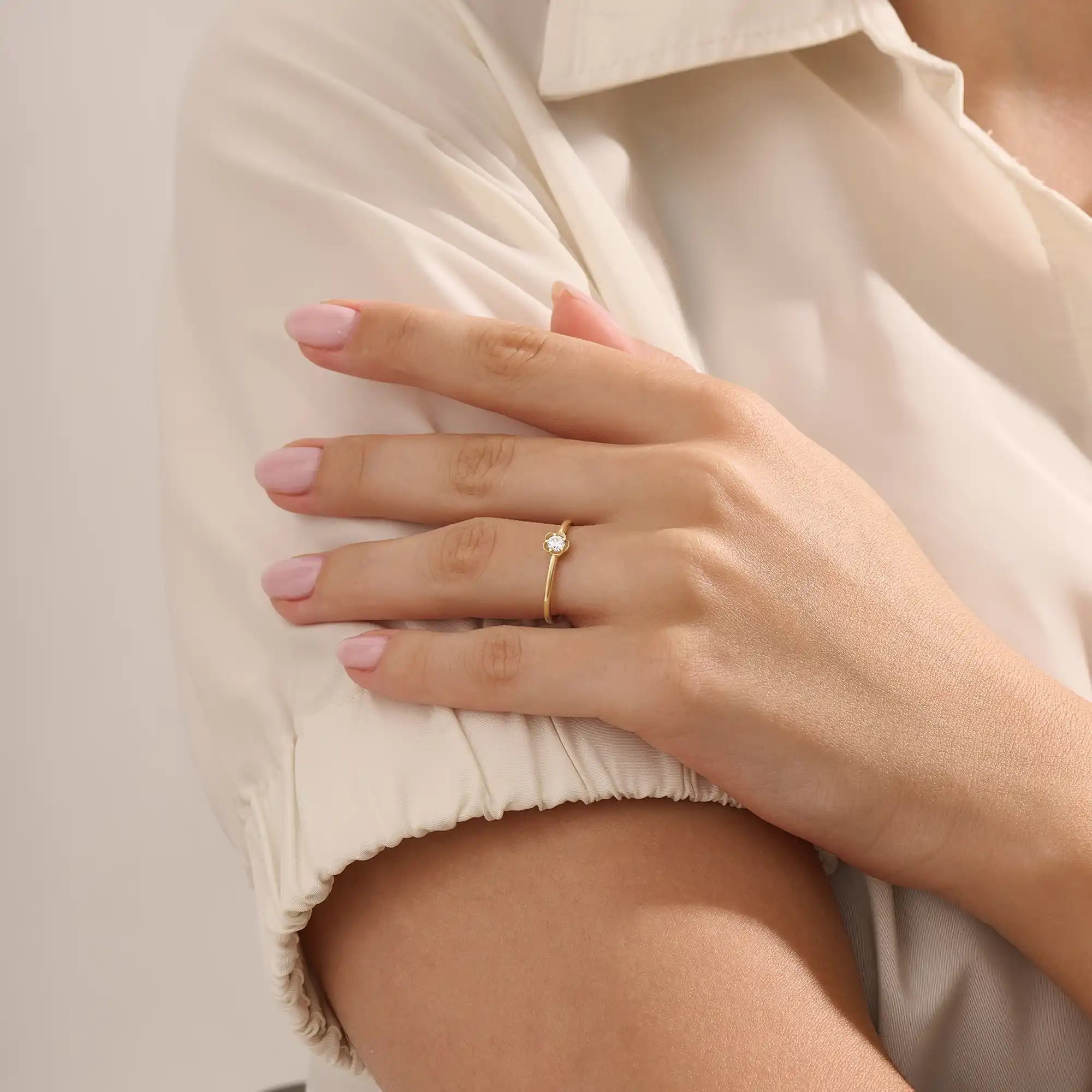 Model wears a 14k solid gold solitaire engagement or promise ring with a small flower motif. Elegant and subtle design for women’s daily wear or special occasions.