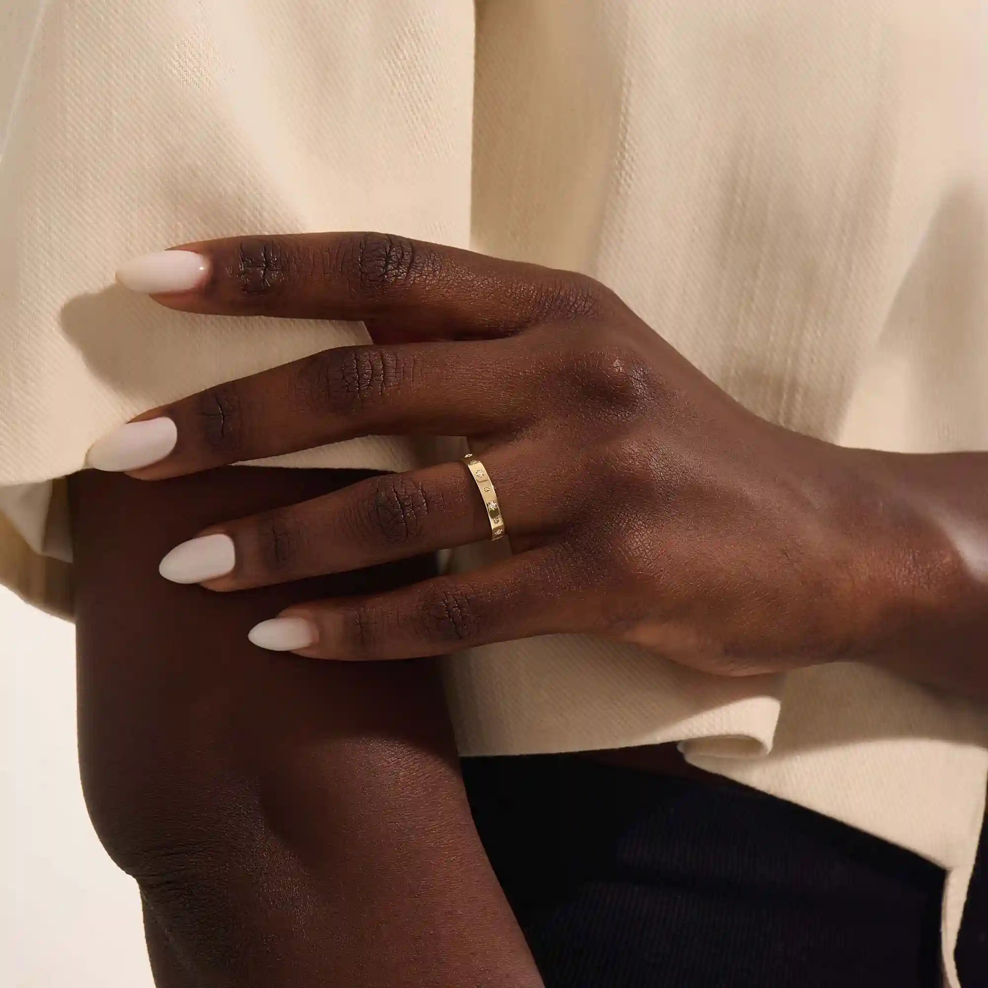 Close-up of a woman wearing a 14k solid yellow gold wedding band decorated with tiny moissanite-set star motifs, styled alone for an understated yet whimsical celestial look.