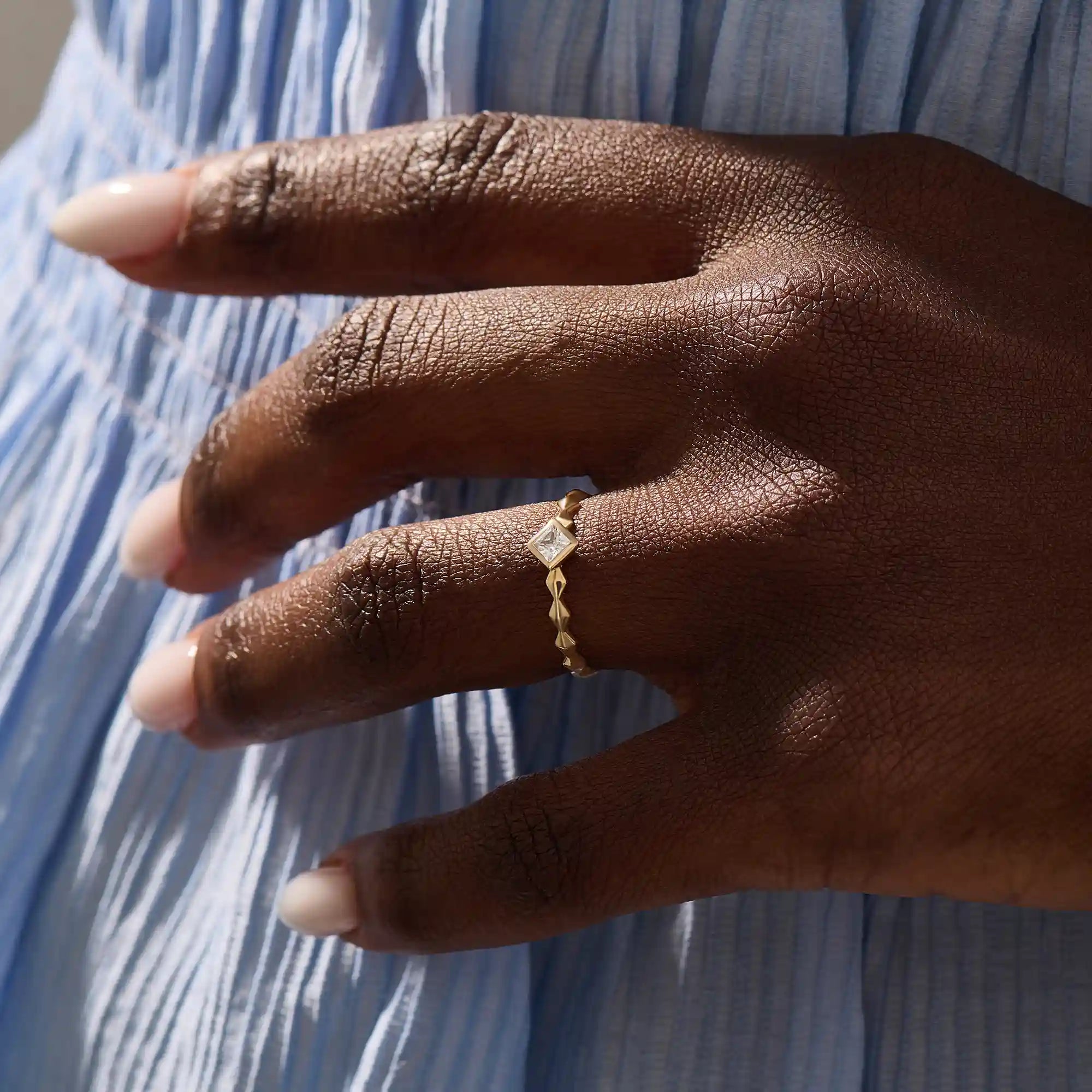 Model wears a bezel set princess square cut solitaire engagement ring in 14k solid gold. Minimalist and timeless bridal style.