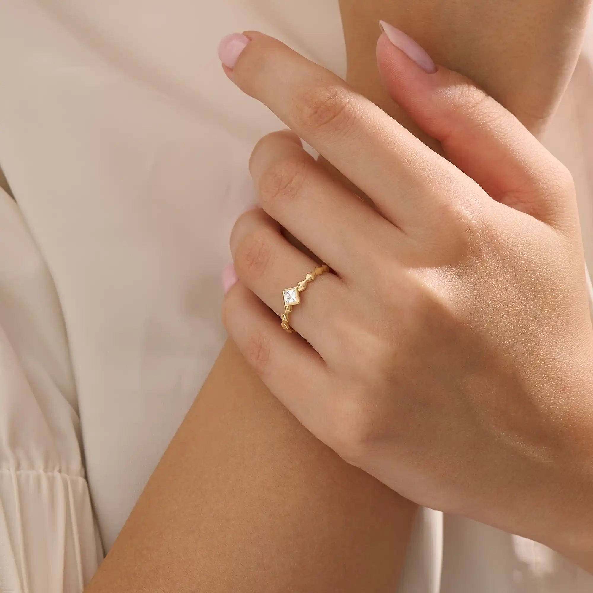 Model wears a bezel set princess square cut solitaire engagement ring in 14k solid gold. Minimalist and timeless bridal style.