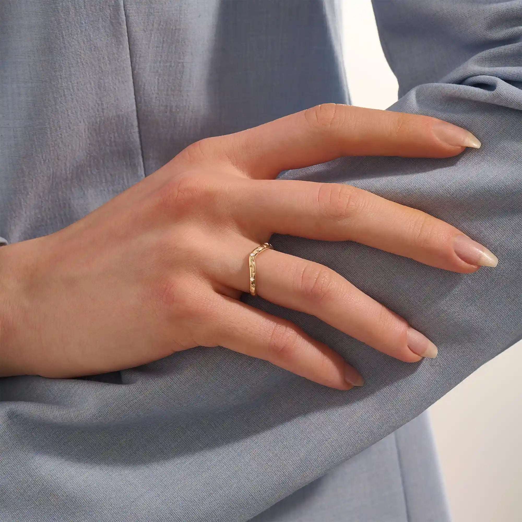 Model wears a celestial curve ring in 14k gold with sparkling moissanite stars. A whimsical and radiant stacking piece for a magical touch.