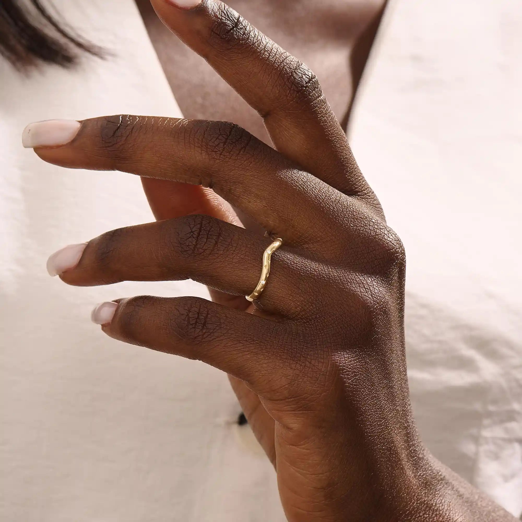 Model wears a celestial curve ring in 14k gold with sparkling moissanite stars. A whimsical and radiant stacking piece for a magical touch.