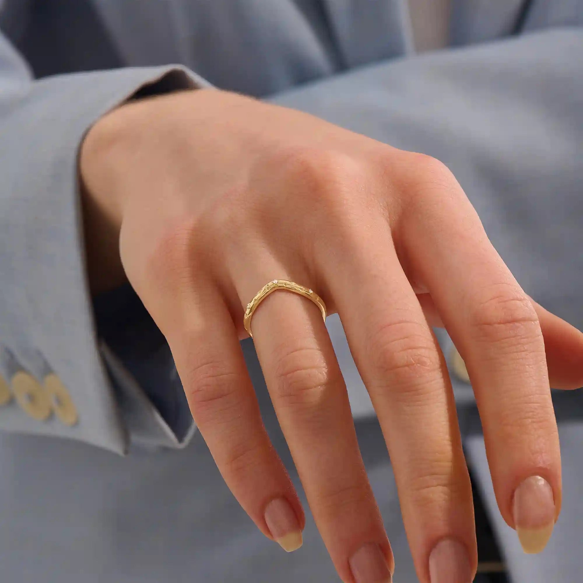 Model wears a celestial curve ring in 14k gold with sparkling moissanite stars. A whimsical and radiant stacking piece for a magical touch.