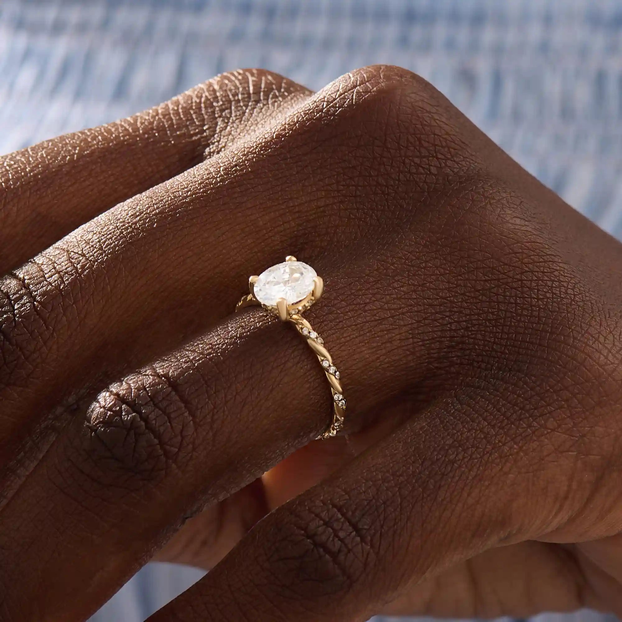 Model wears a chunky solitaire oval moissanite engagement ring in 14k solid gold. Minimalist yet bold bridal style.