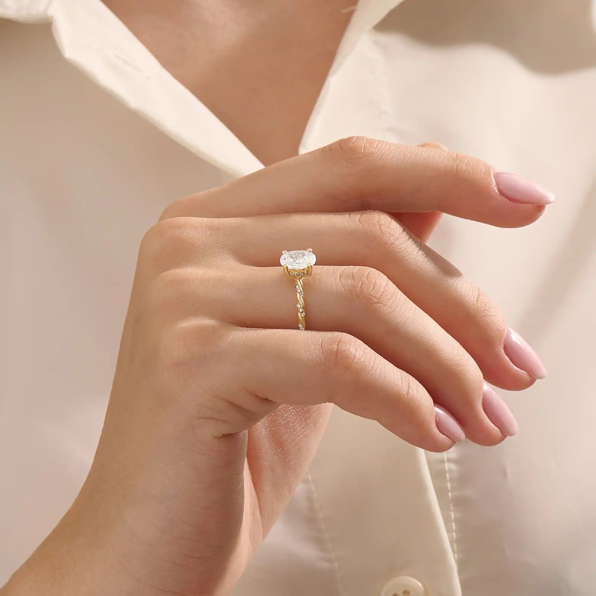 Model wears a chunky solitaire oval moissanite engagement ring in 14k solid gold. Minimalist yet bold bridal style.