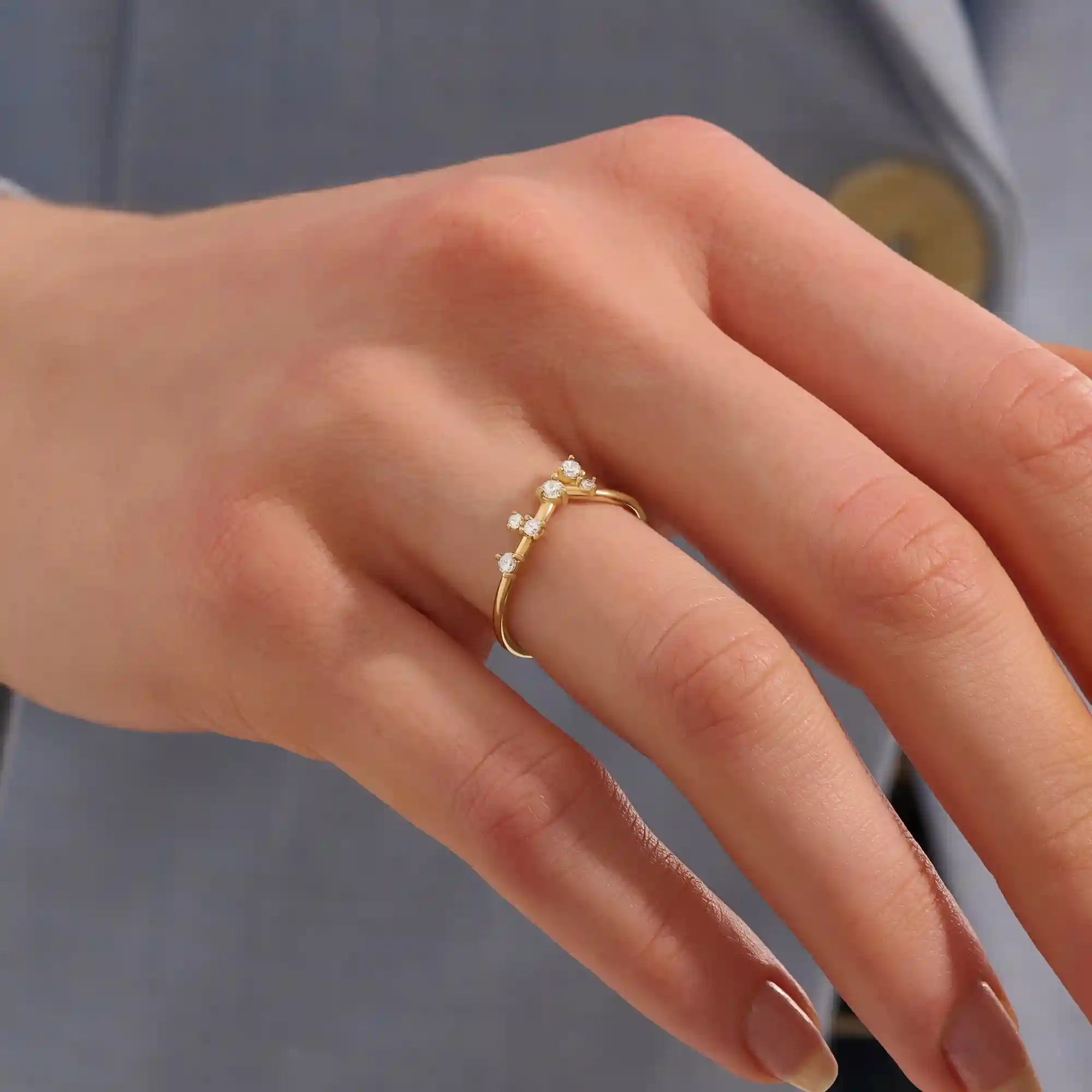Model wears a curved 14k gold nesting ring with scattered moissanites. A delicate stacking piece that adds soft brilliance to any ring stack.