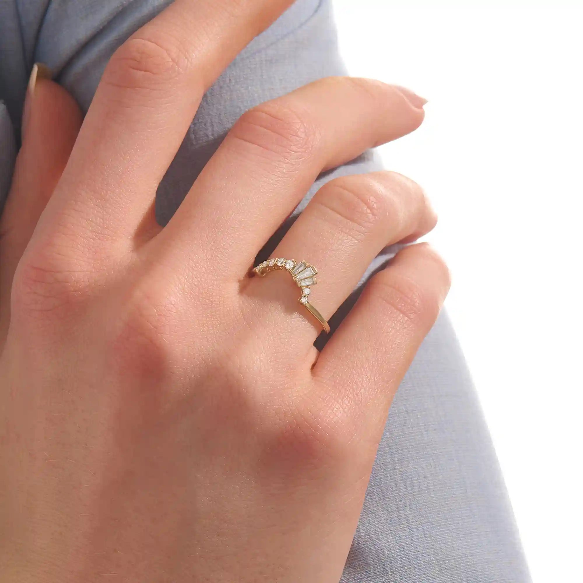 Model wears a curved gold ring adorned with baguette moissanites in an arch design. Sleek and contemporary, perfect for layering with solitaires.